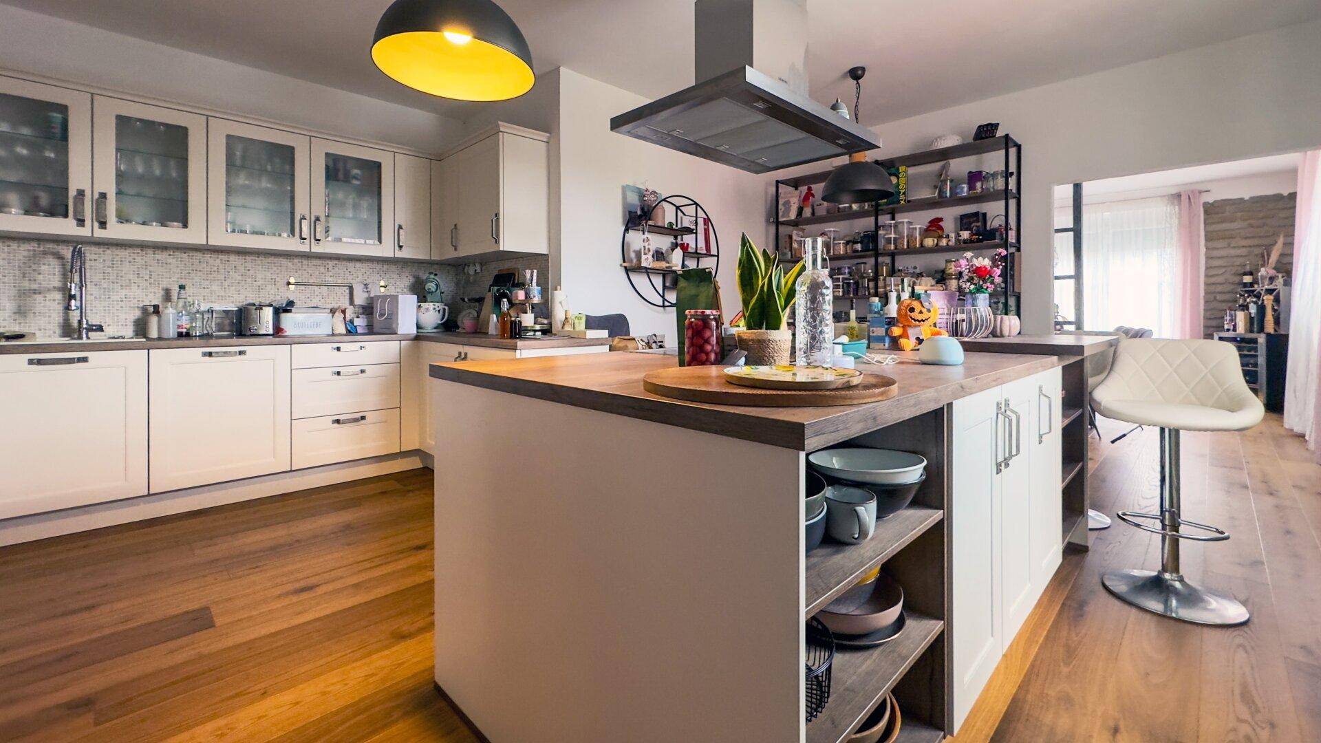 Helle, offene Küche mit Kücheninsel, Holztheke und modernen Einbaugeräten.