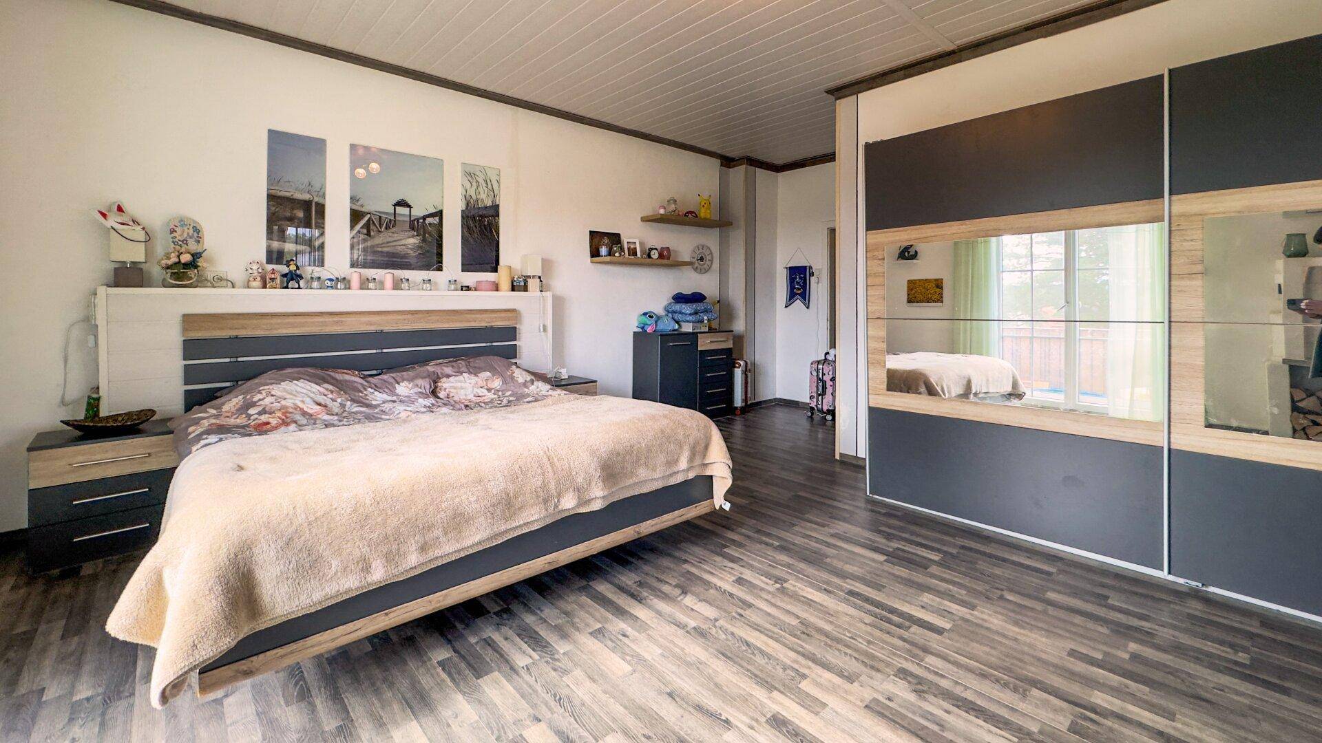 Geräumiges Schlafzimmer mit großem Doppelbett, Schiebetürenschrank und modernem Design.