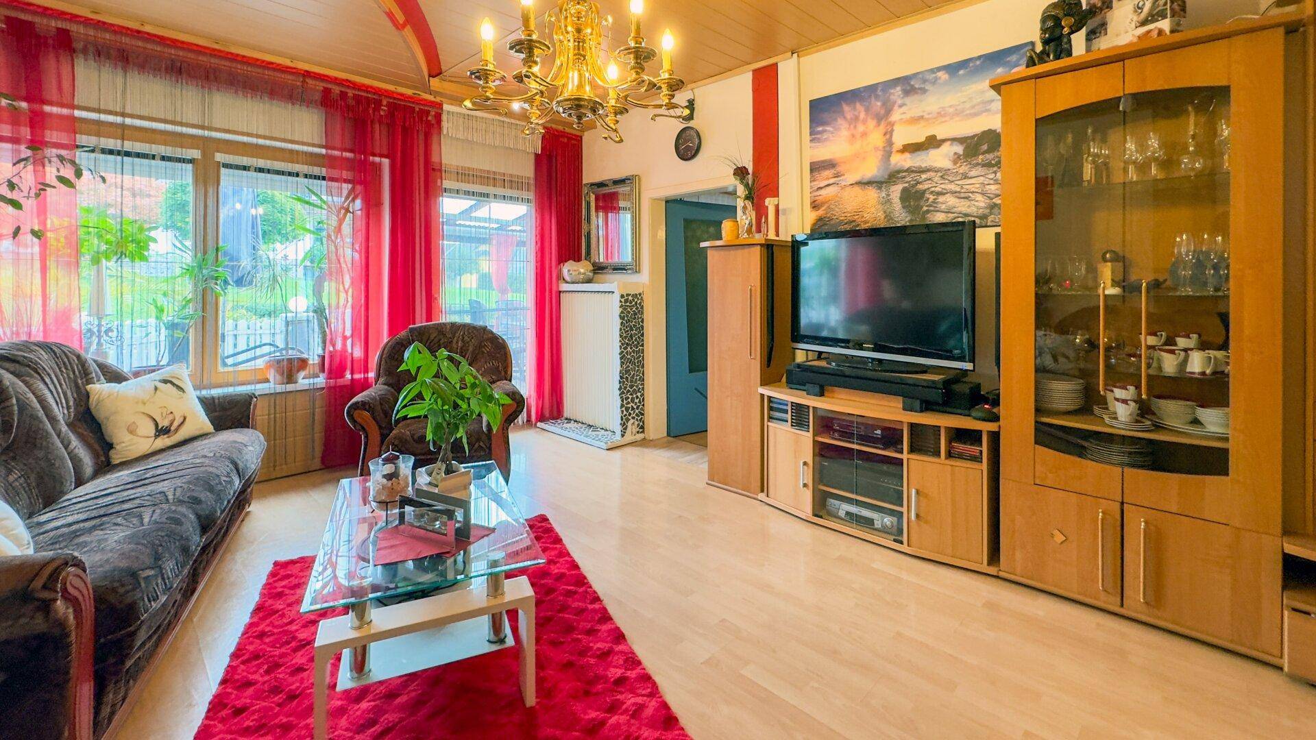 Gemütliches Wohnzimmer mit Holzboden, Fernseher und traditionellen Möbeln.