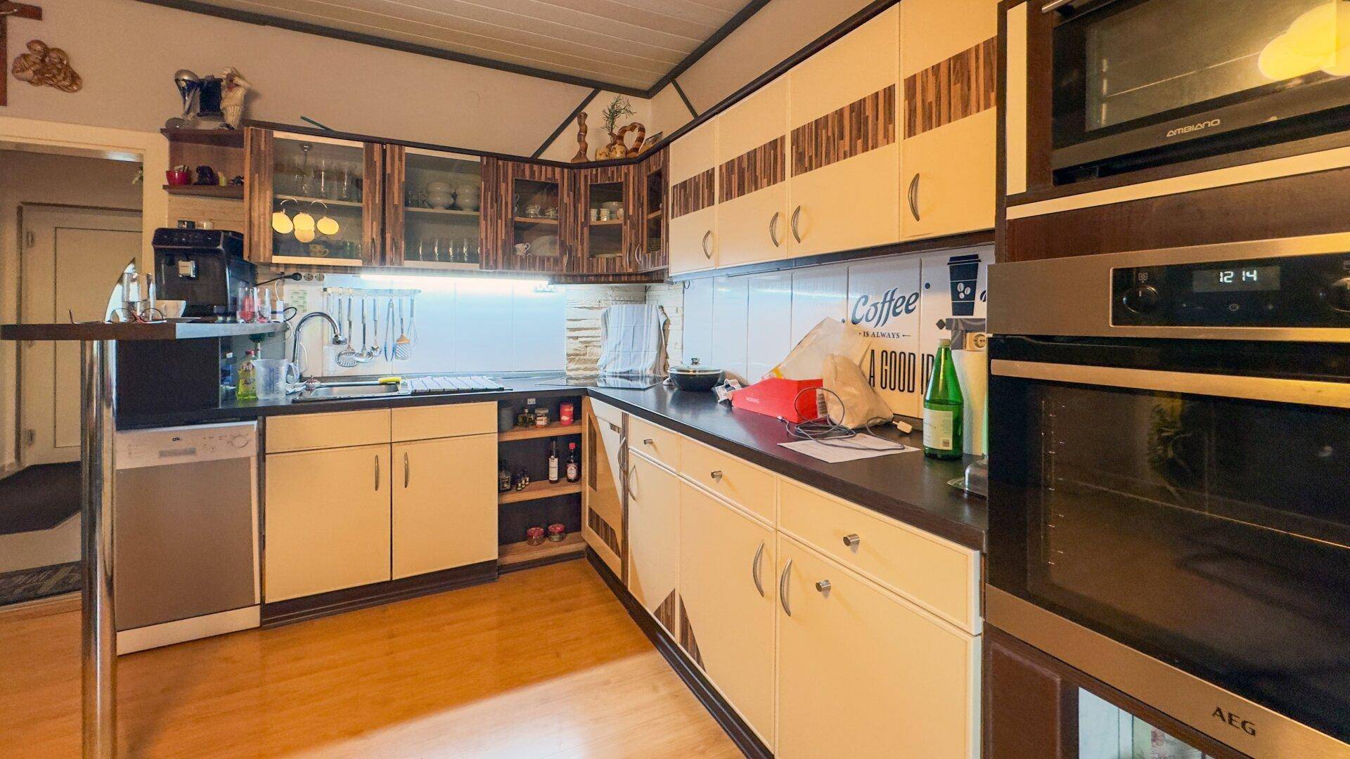 Funktionale Küche mit Holzboden, Einbaugeräten und ausreichend Arbeitsfläche.