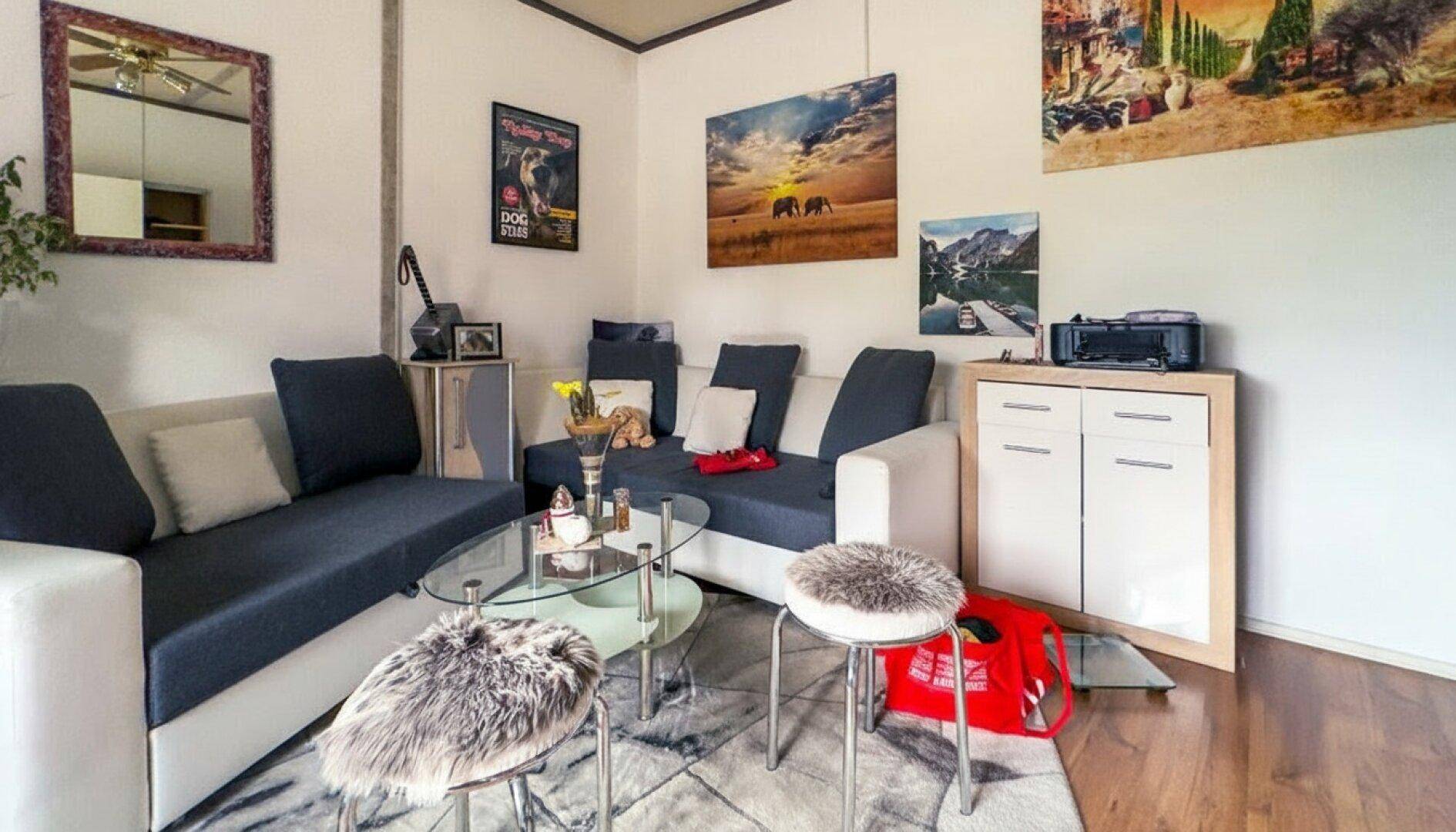 Gemütliches Wohnzimmer mit zwei Sofas, einem Couchtisch und verschiedenen Kunstwerken an den Wänden.