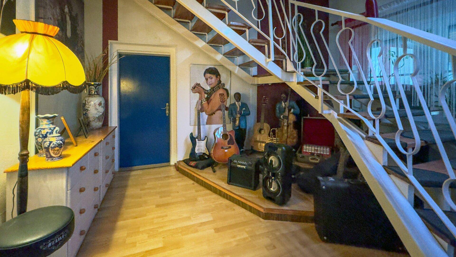 Detailansicht der Treppe und einer Sammlung von Gitarren und anderen Musikinstrumenten im Flurbereich.