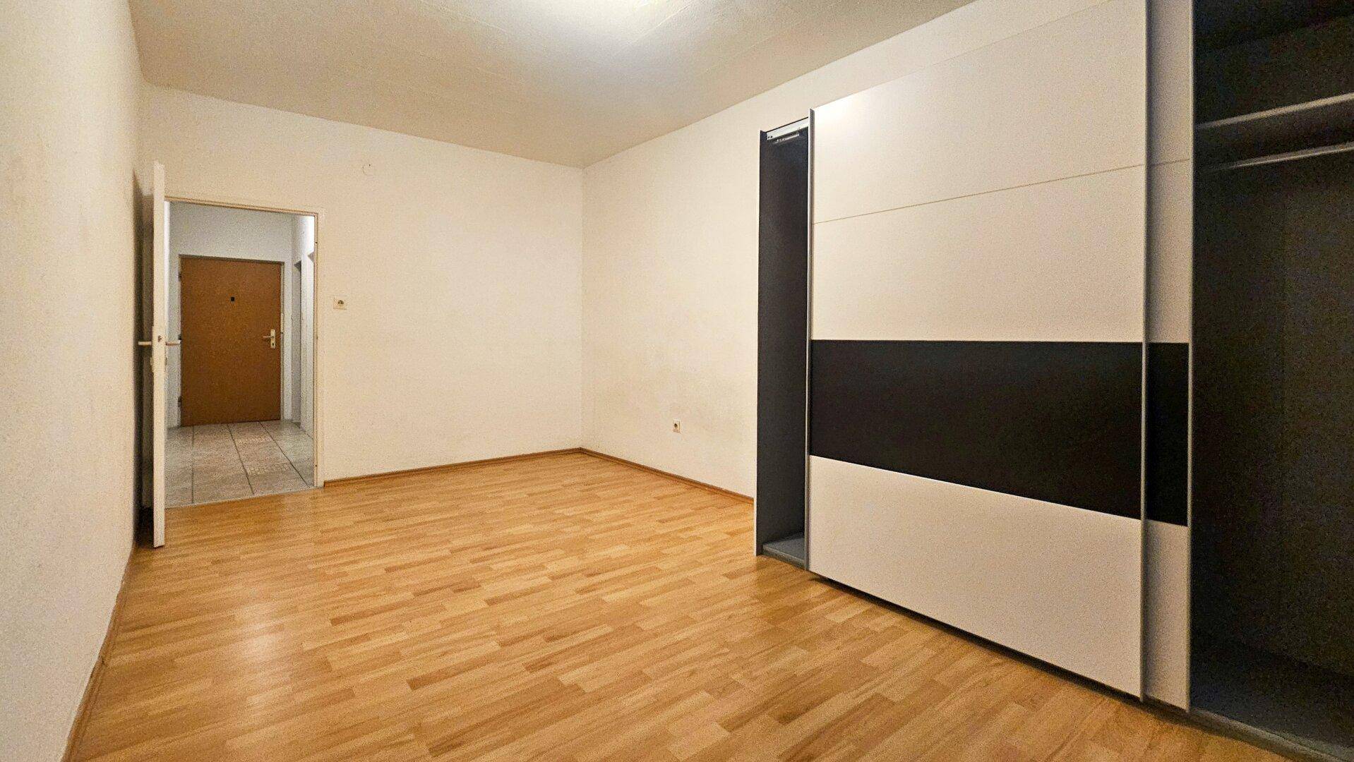 Geräumiges Schlafzimmer mit Parkettboden und einem modernen Schiebetürenschrank.