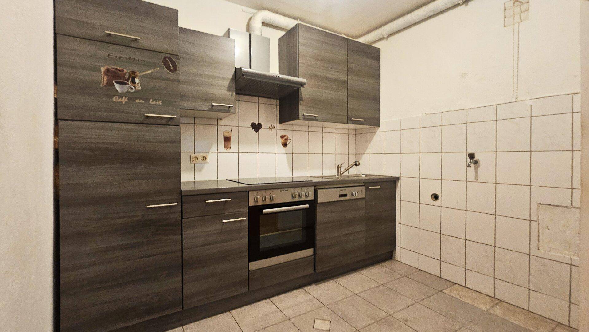 Moderne Einbauküche mit dunklen Schränken, integrierten Geräten und Fliesenboden.