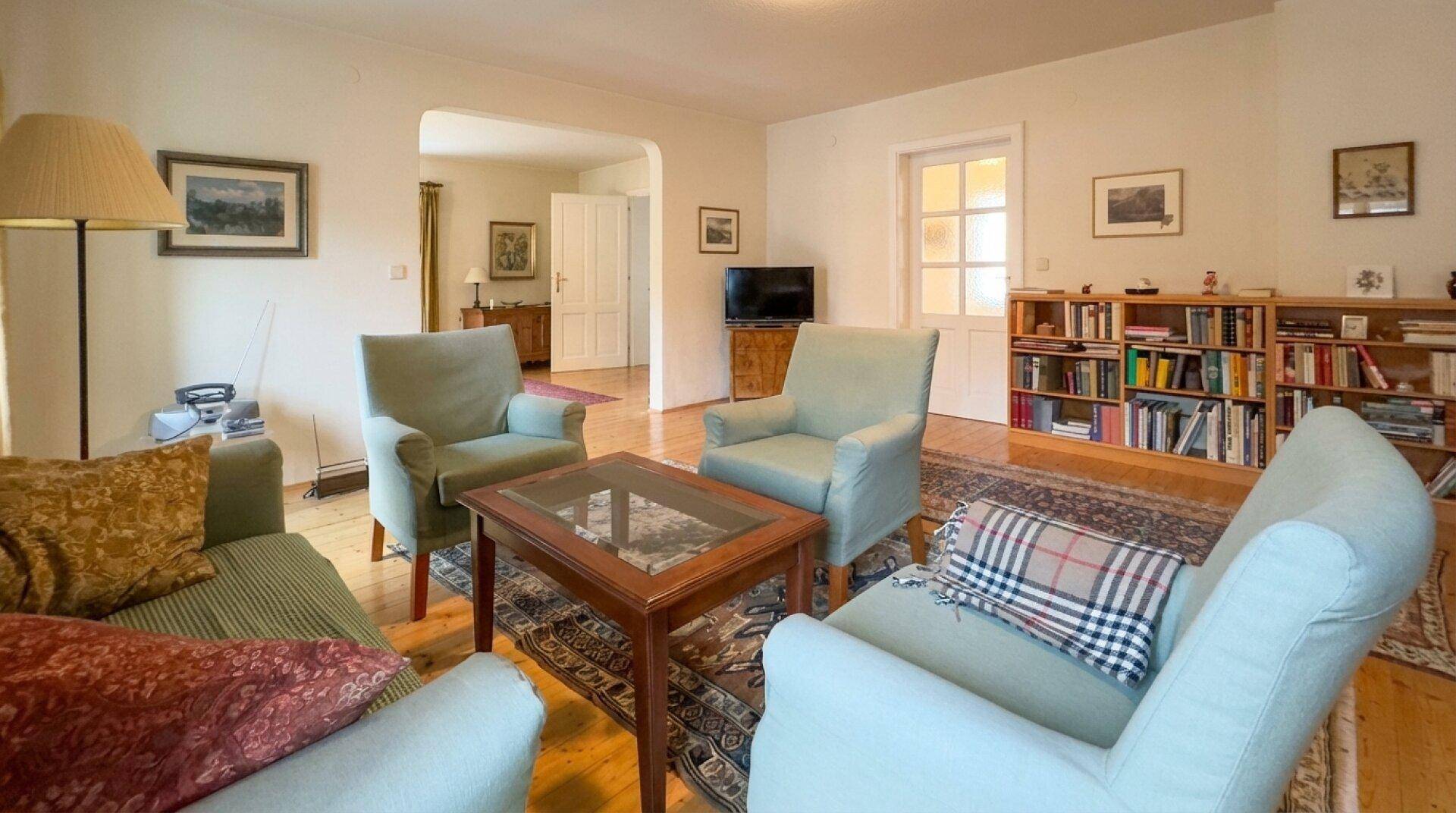 Helles Wohnzimmer mit Holzboden, bequemen Sesseln und Bücherregal.