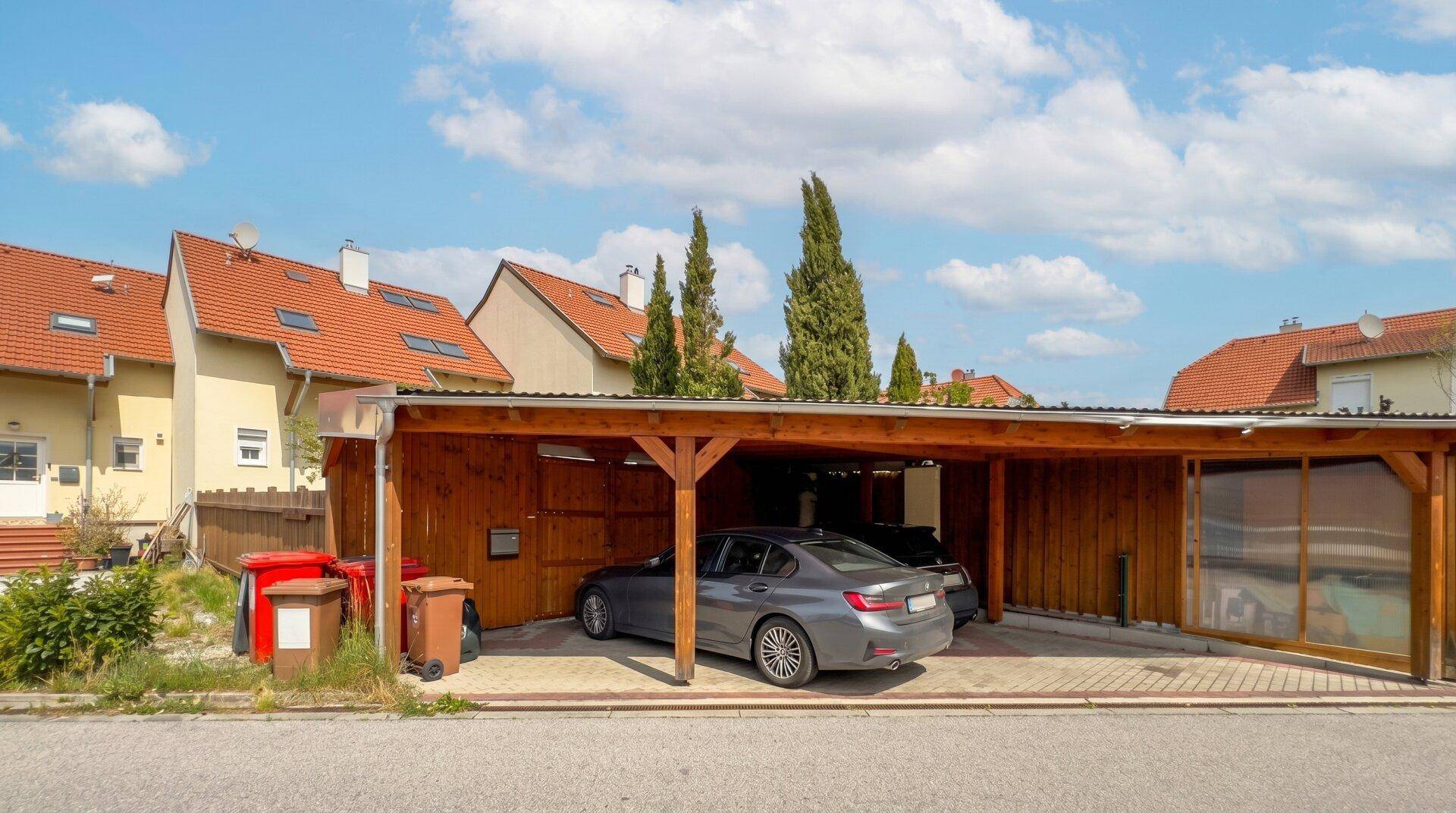 Geräumiger Holzcarport mit Platz für zwei Fahrzeuge, umgeben von Wohngebäuden.