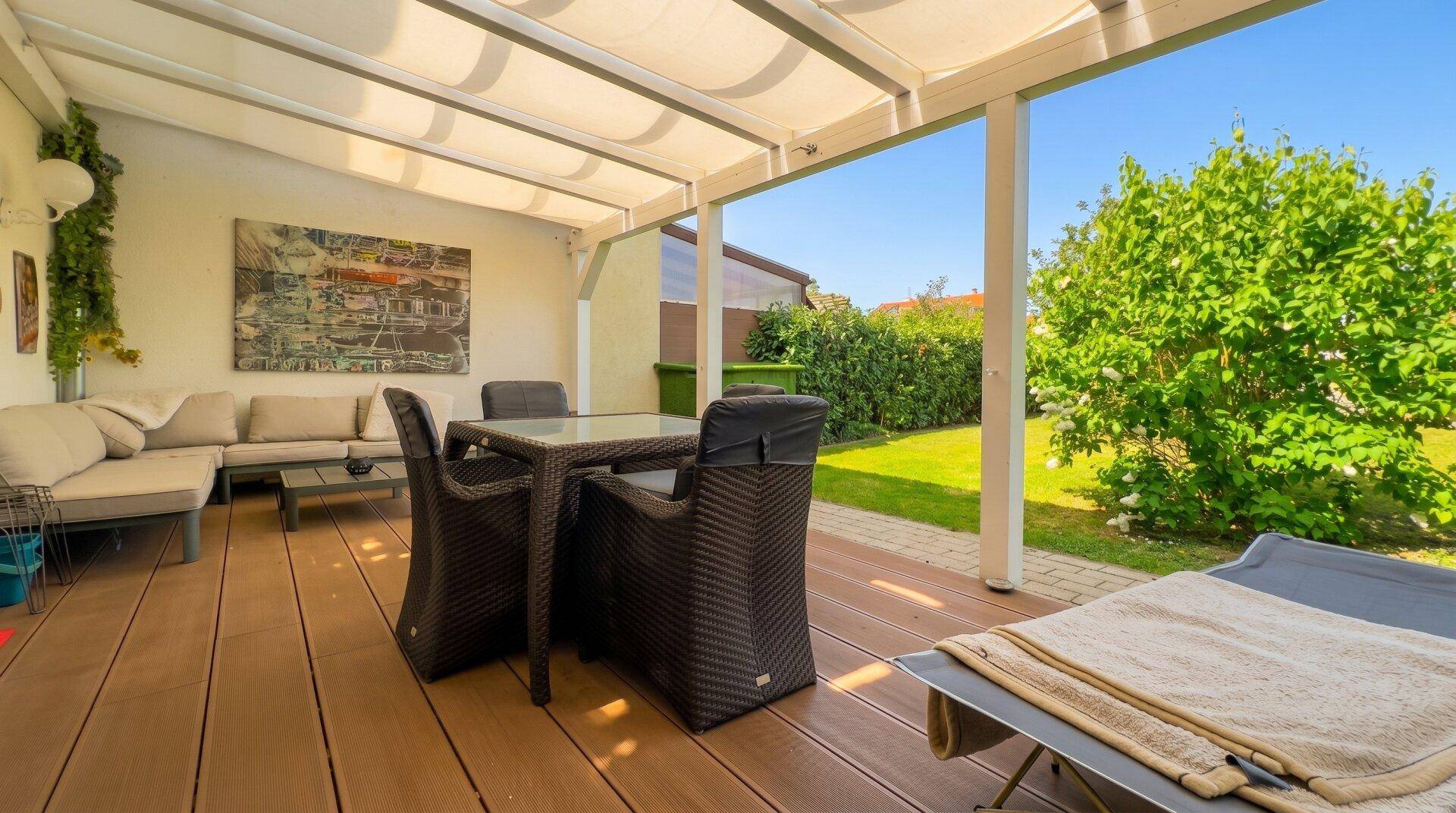 Große überdachte Terrasse mit bequemen Gartenmöbeln und direktem Zugang zum grünen Garten.