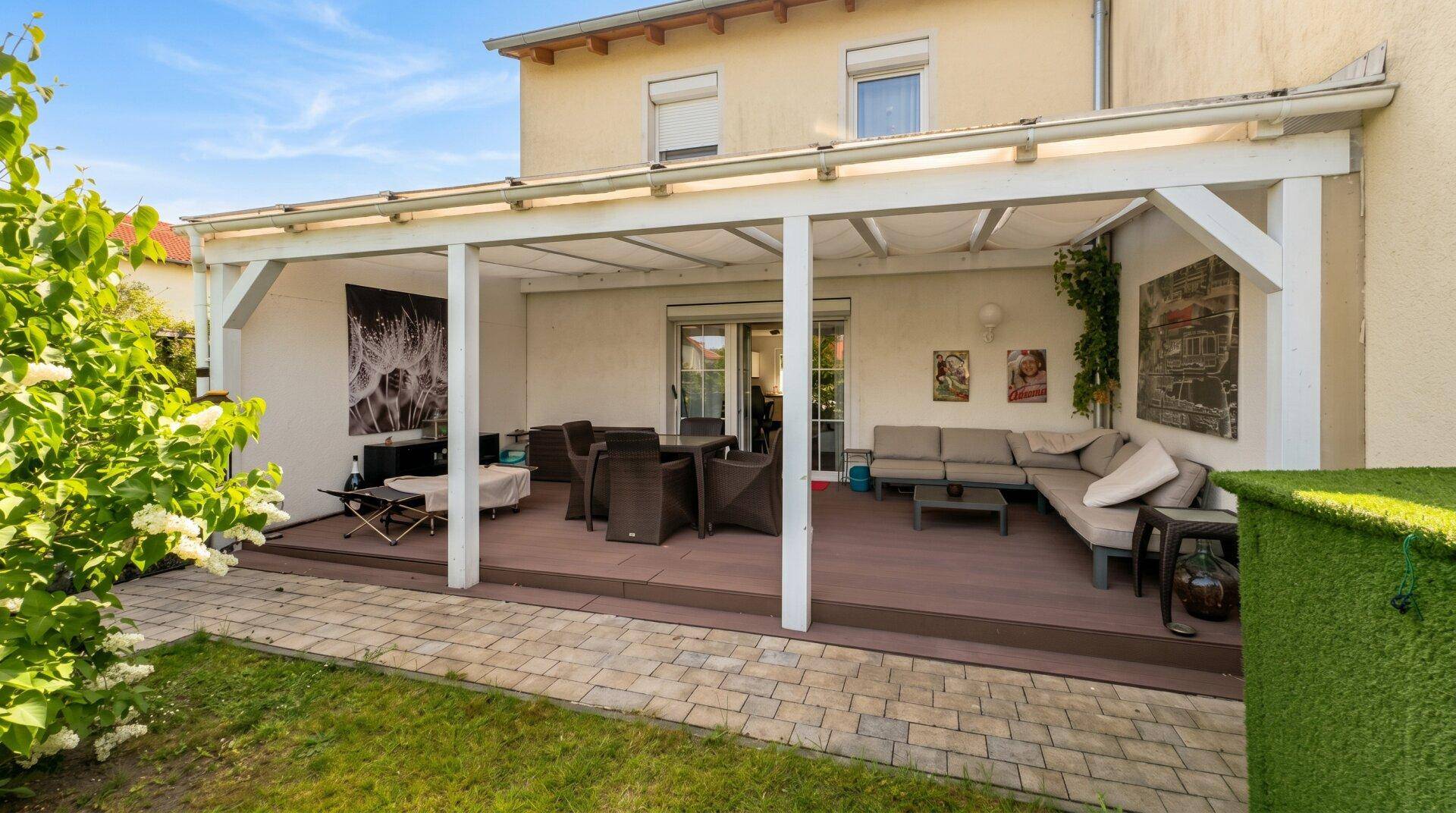 Überdachte Terrasse mit Lounge- und Essbereich, ideal für Entspannung im Freien und Gartenblick.