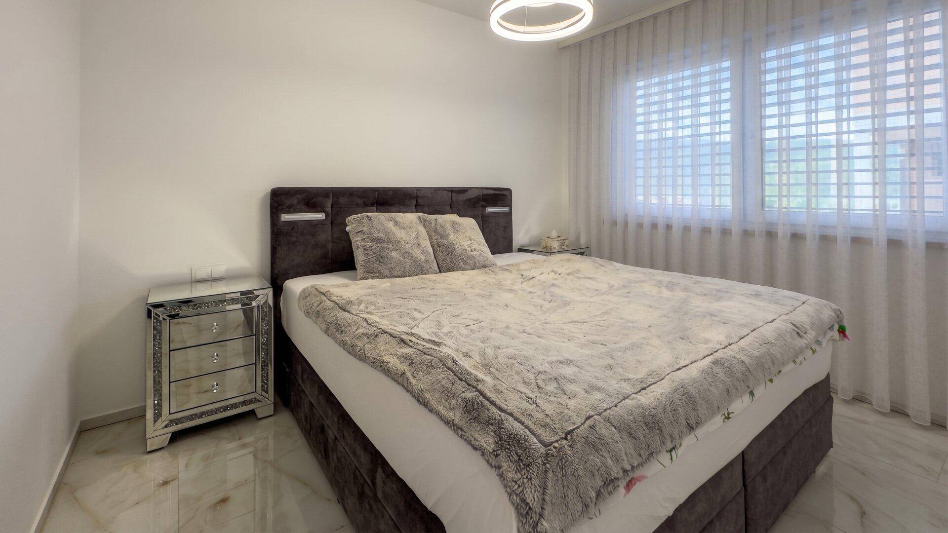Gemütliches Schlafzimmer mit großem Bett, Nachttischen und glänzendem Marmorboden.