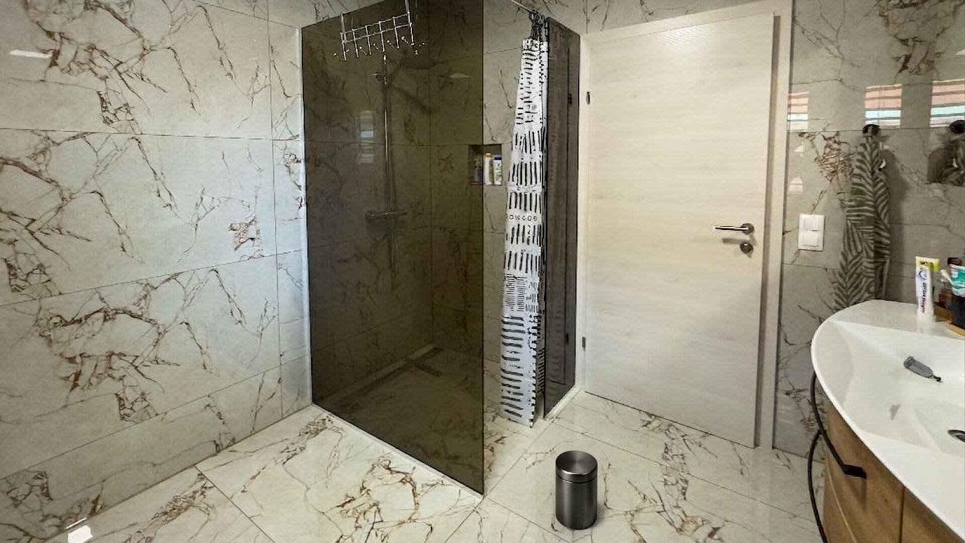Geräumige begehbare Dusche mit Glasabtrennung und Marmorfliesen im modernen Badezimmer.