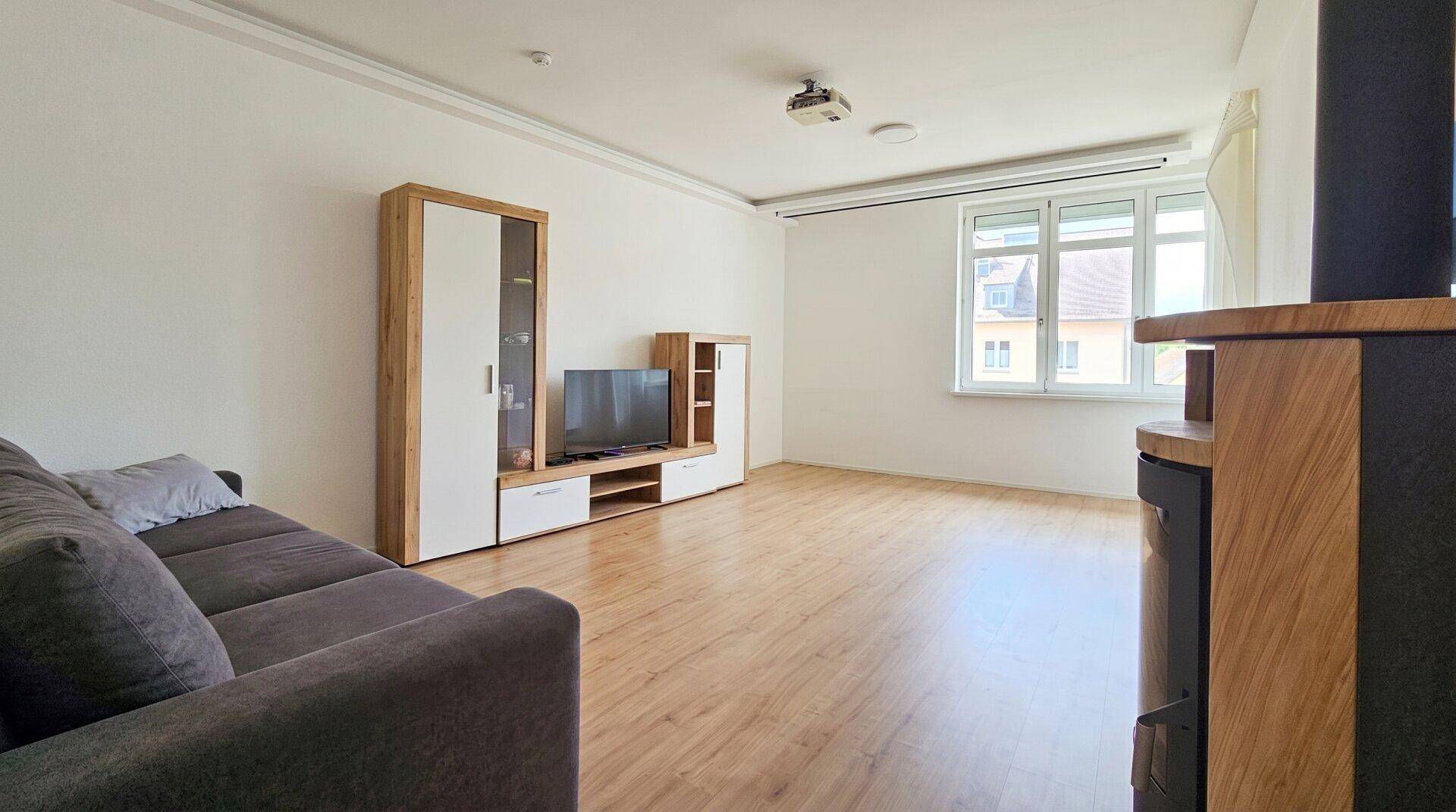 Wohnzimmer mit Sofa, TV-Möbeln und Holzboden, bietet eine helle Atmosphäre.