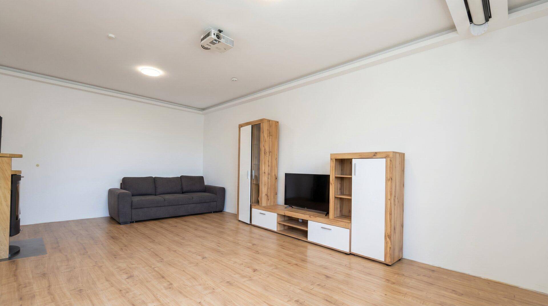 Helles Wohnzimmer mit Holzboden, Sofa, TV-Möbeln und Klimaanlage.