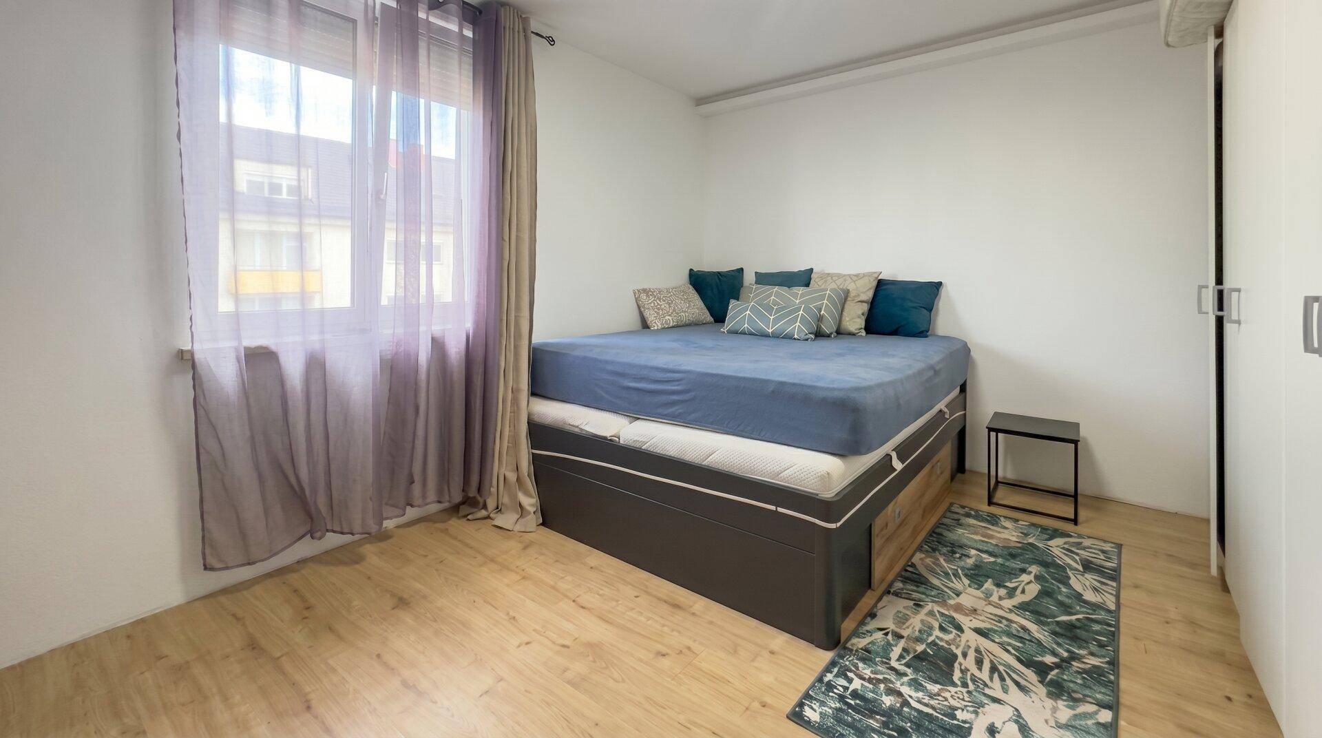 Schlafzimmer mit Holzboden, großem Bett und Vorhängen, bietet eine ruhige Atmosphäre.
