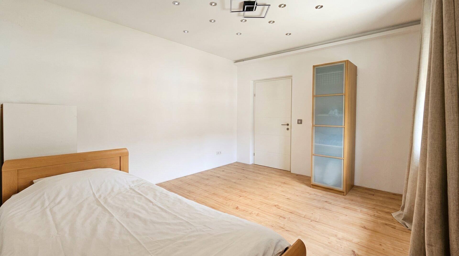 Schlafzimmer mit Holzboden, Doppelbett und Einbauschrank, bietet viel Stauraum.