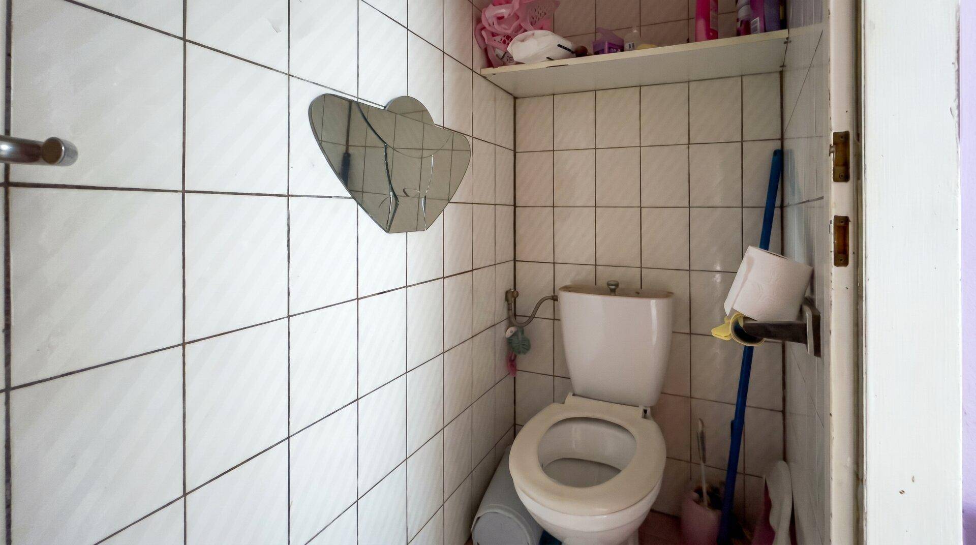 Kleines WC mit Fliesen und Toilette, das eine Modernisierung benötigt.