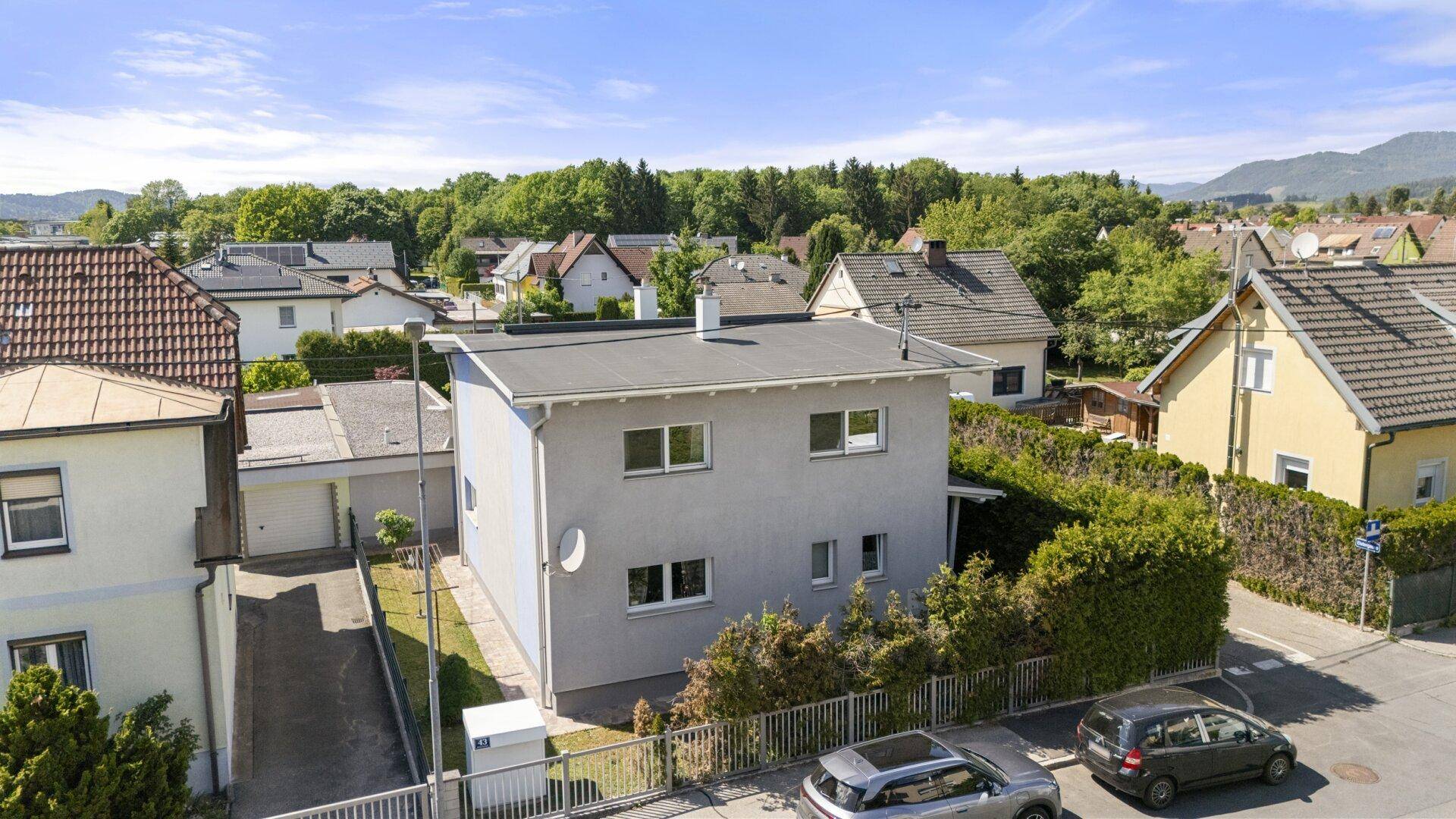 Luftaufnahme des modernen Hauses mit Flachdach und angrenzender Straße in einer ruhigen Wohngegend.
