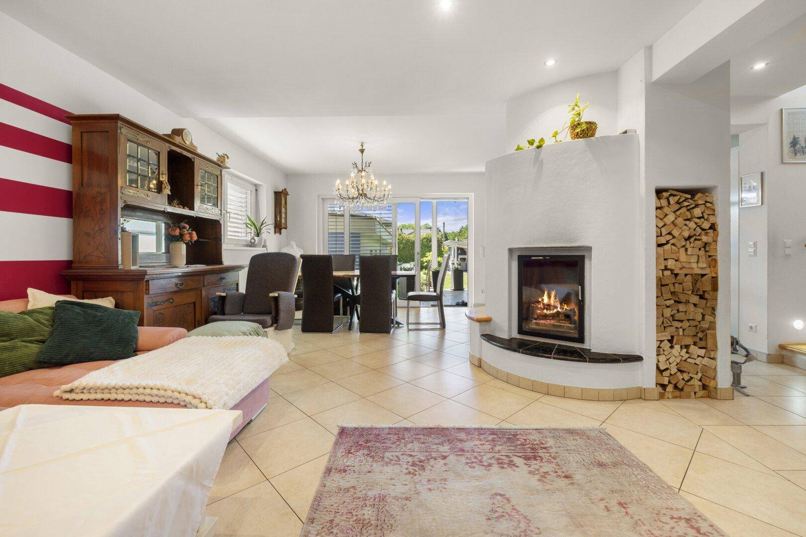 Heller Wohnbereich mit modernem Kamin, Holzregal und Zugang zum Essbereich und Garten.