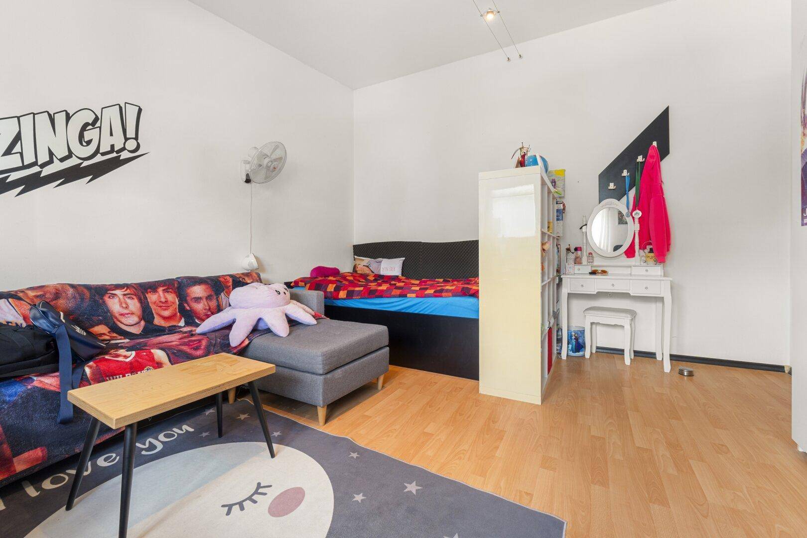 Jugendzimmer mit Sofa, Bett und einem Schminktisch, ideal für junge Bewohner.