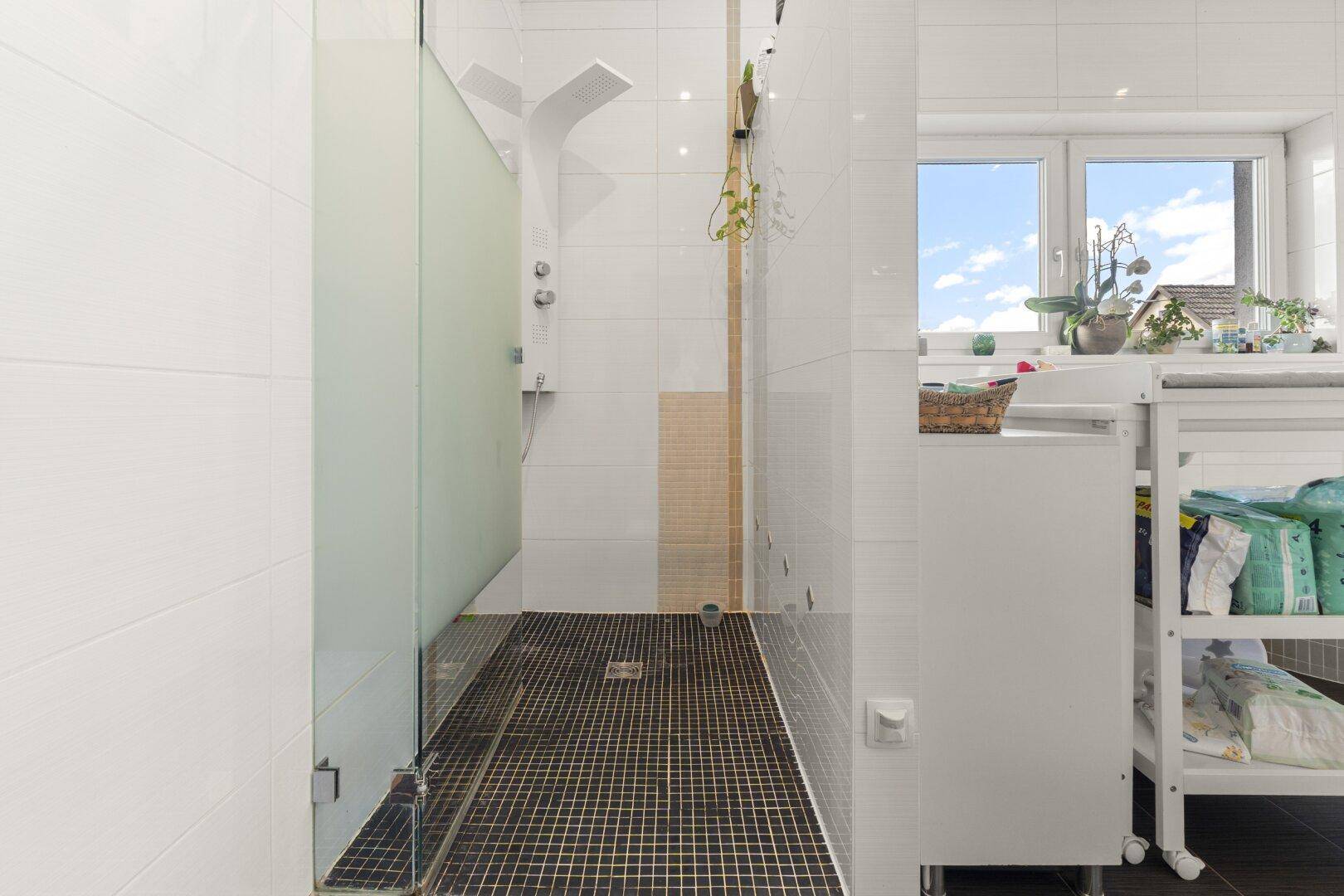 Geräumige begehbare Dusche mit Glasabtrennung und Fenster für viel Tageslicht.