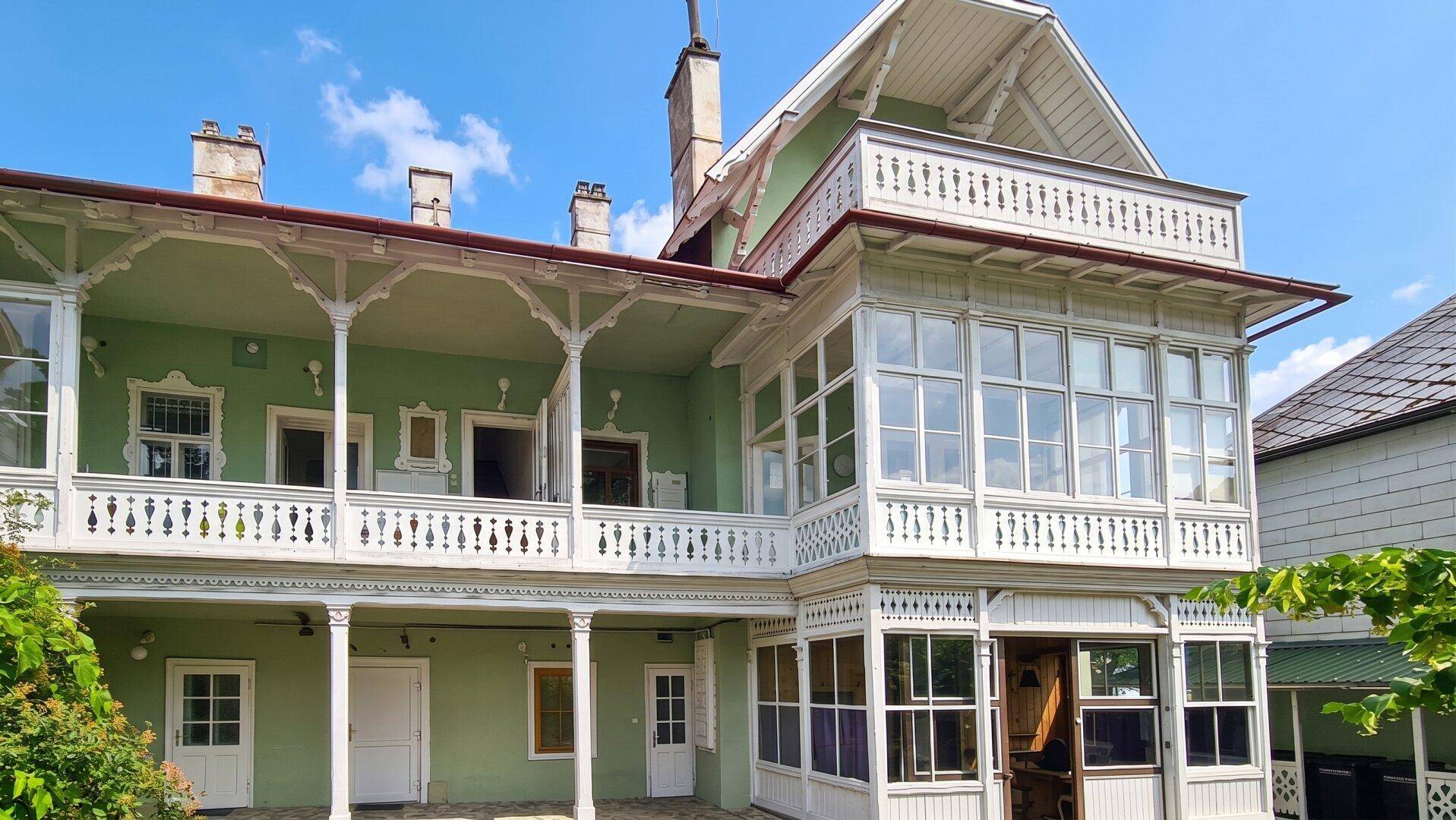 Detailansicht der historischen Fassade mit kunstvollen Holzverzierungen und mehreren Balkonen.