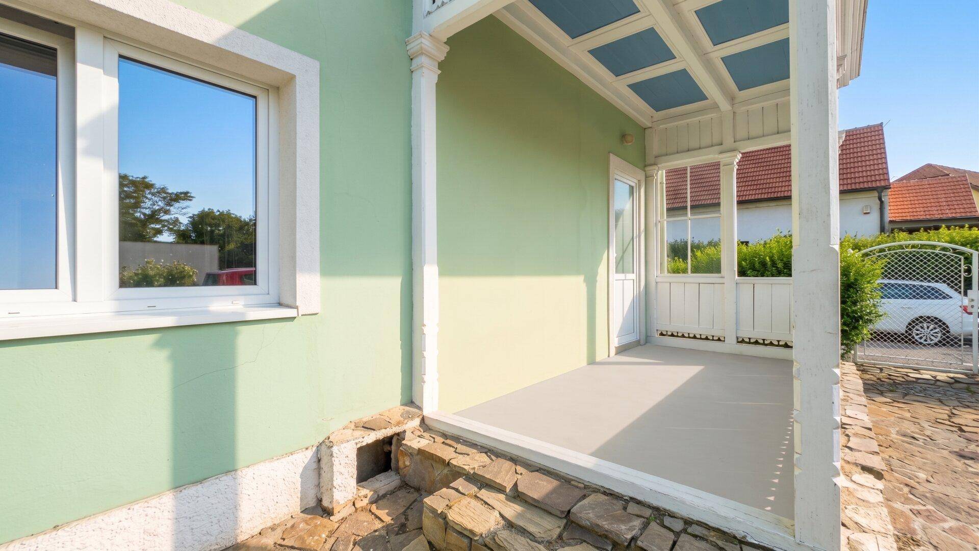 Überdachte Terrasse mit Steinboden und Blick auf die Umgebung, ideal für entspannte Stunden.