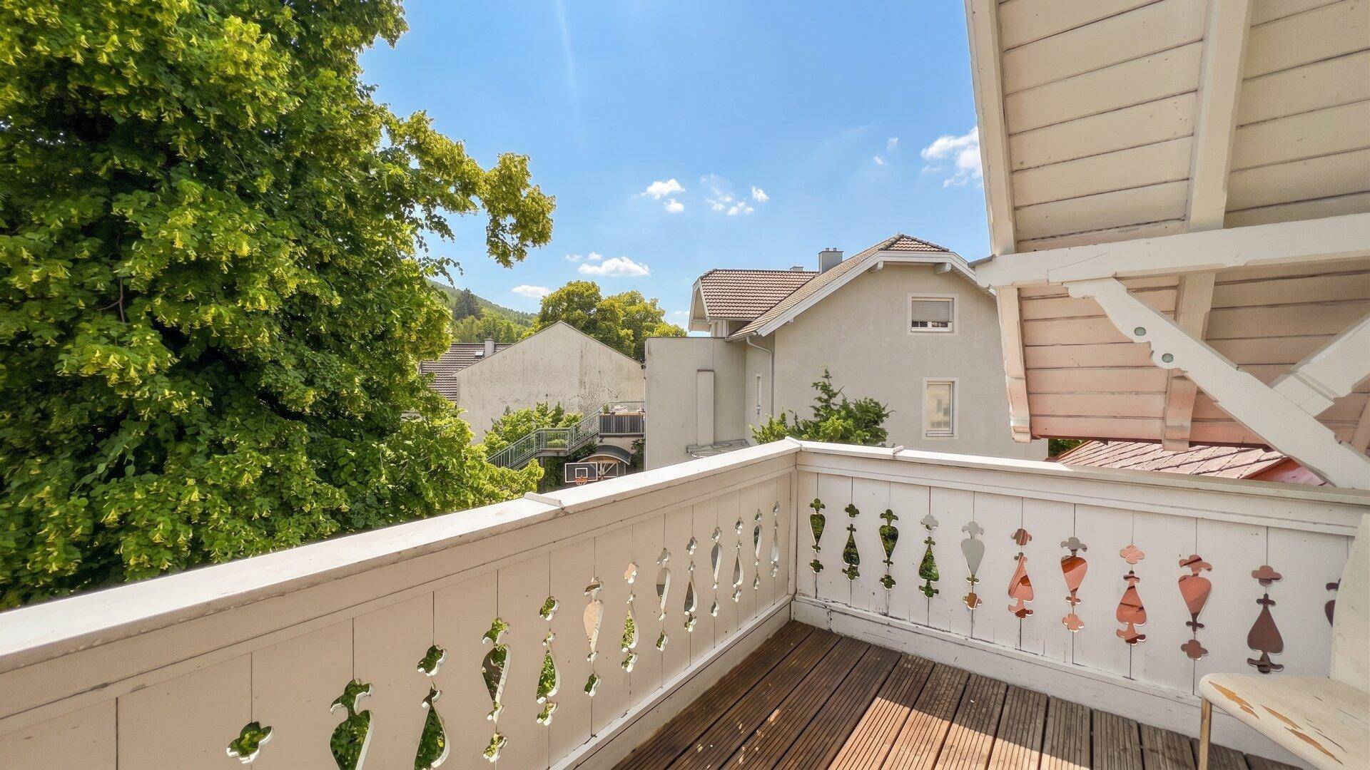 Balkon mit Holzboden und kunstvollem Geländer, bietet einen schönen Blick ins Grüne.