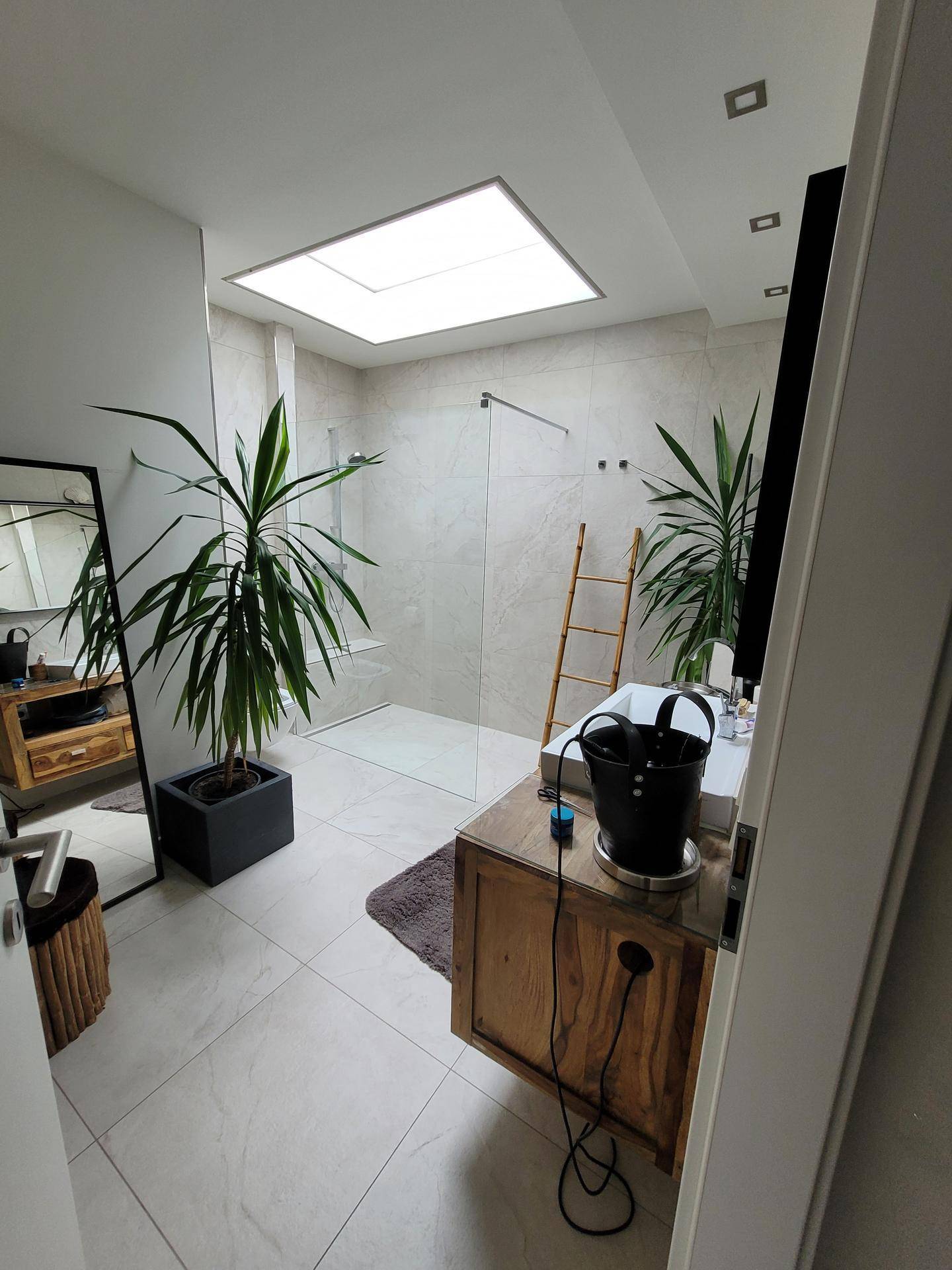 Geräumiges, modernes Badezimmer mit begehbarer Dusche, Holzwaschtisch und hellem Oberlicht.