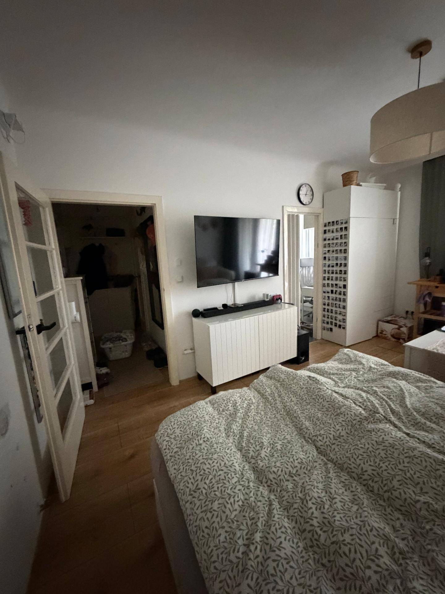 Schlafzimmer mit Bett und Fernseher, mit Zugang zu einem weiteren Raum, hell und funktional.