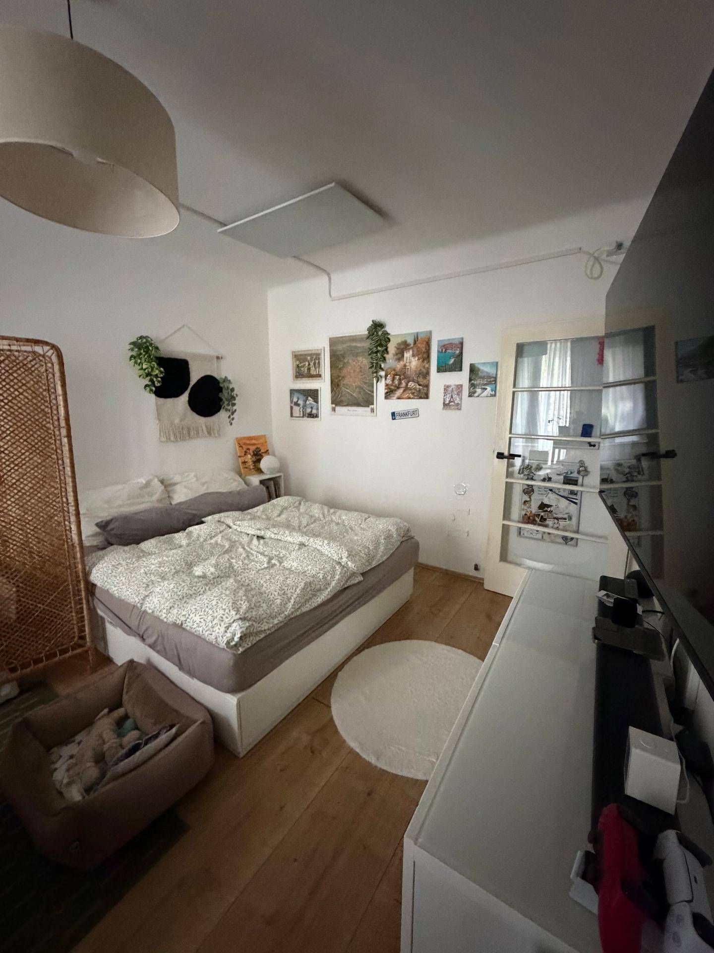 Schlafzimmer mit Doppelbett, Fernseher und dekorativen Bildern an der Wand, mit Holzboden.