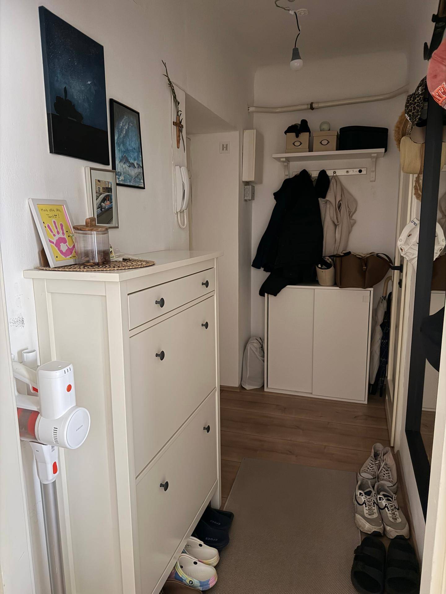 Heller Eingangsbereich mit Schuhschrank, Garderobe und Spiegel, der einen aufgeräumten Eindruck vermittelt.