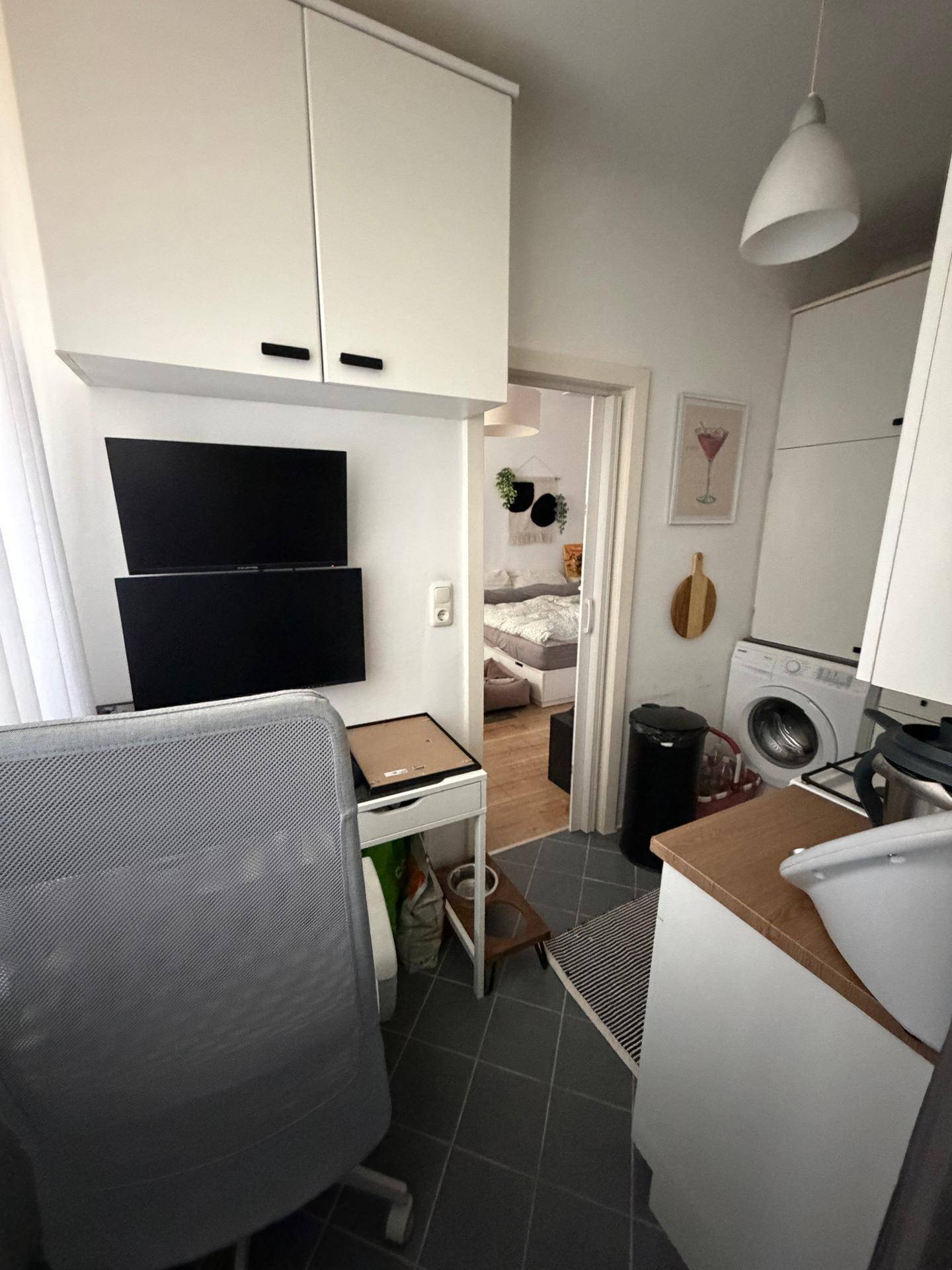 Küchenzeile mit integriertem Arbeitsplatz am Fenster und Zugang zu einem angrenzenden Schlafzimmer.