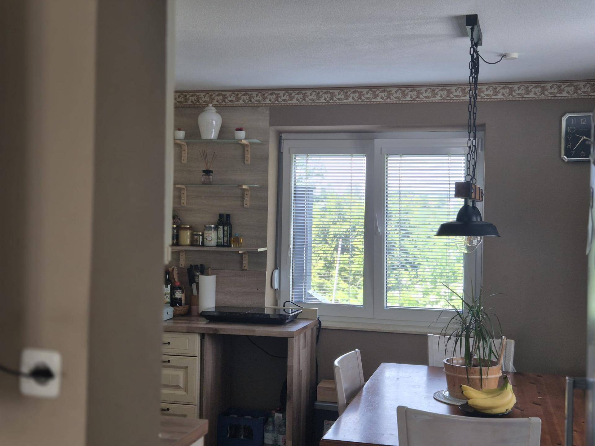 Heller Essbereich mit Holztisch und Blick ins Grüne durch das Fenster.