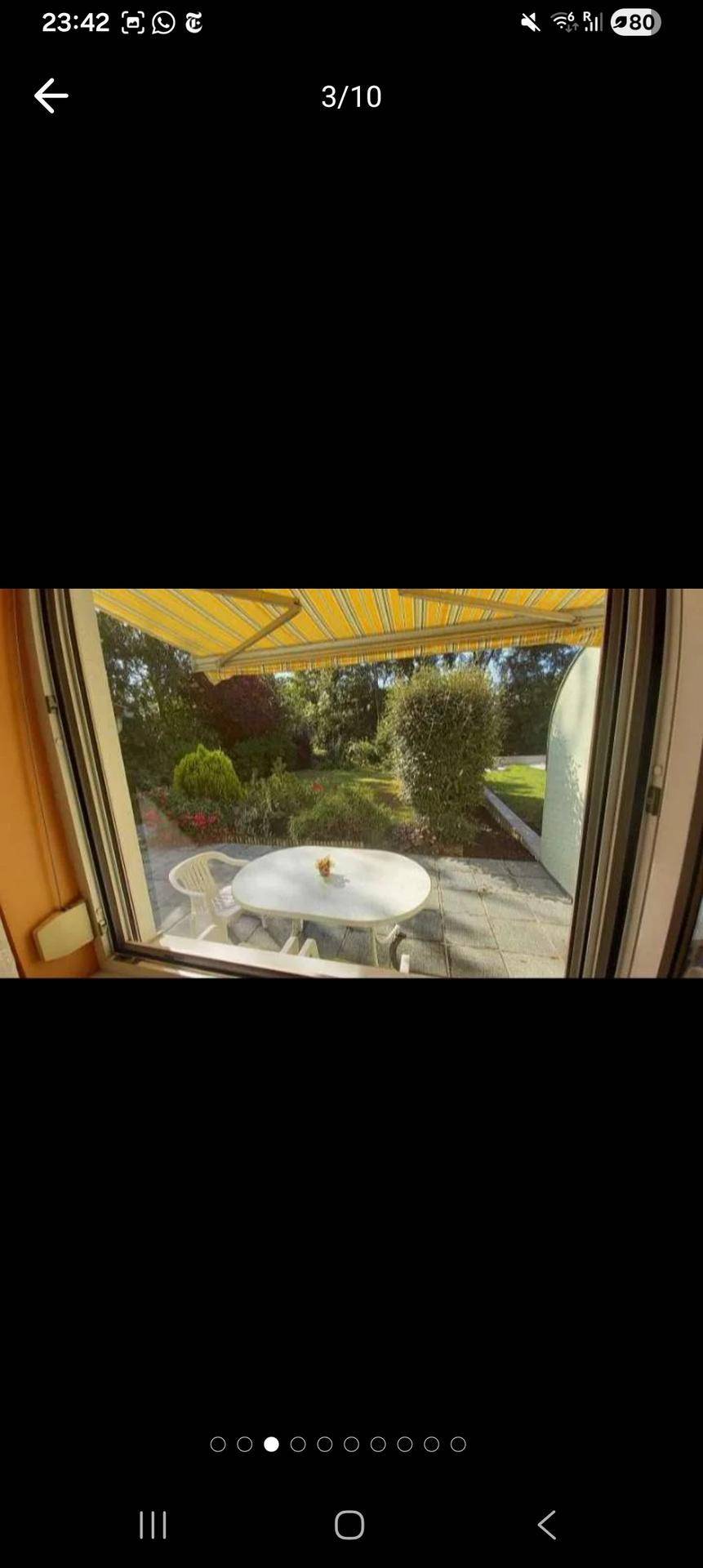 Helle Terrasse mit Gartenmöbeln, Markise und Blick ins Grüne.