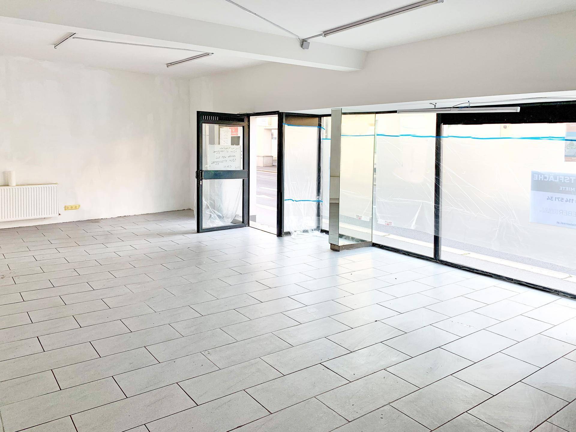 Geräumiger, leerer Ladenbereich mit Fliesenboden und breiter Glasfront, ideal für verschiedene Geschäftskonzepte.