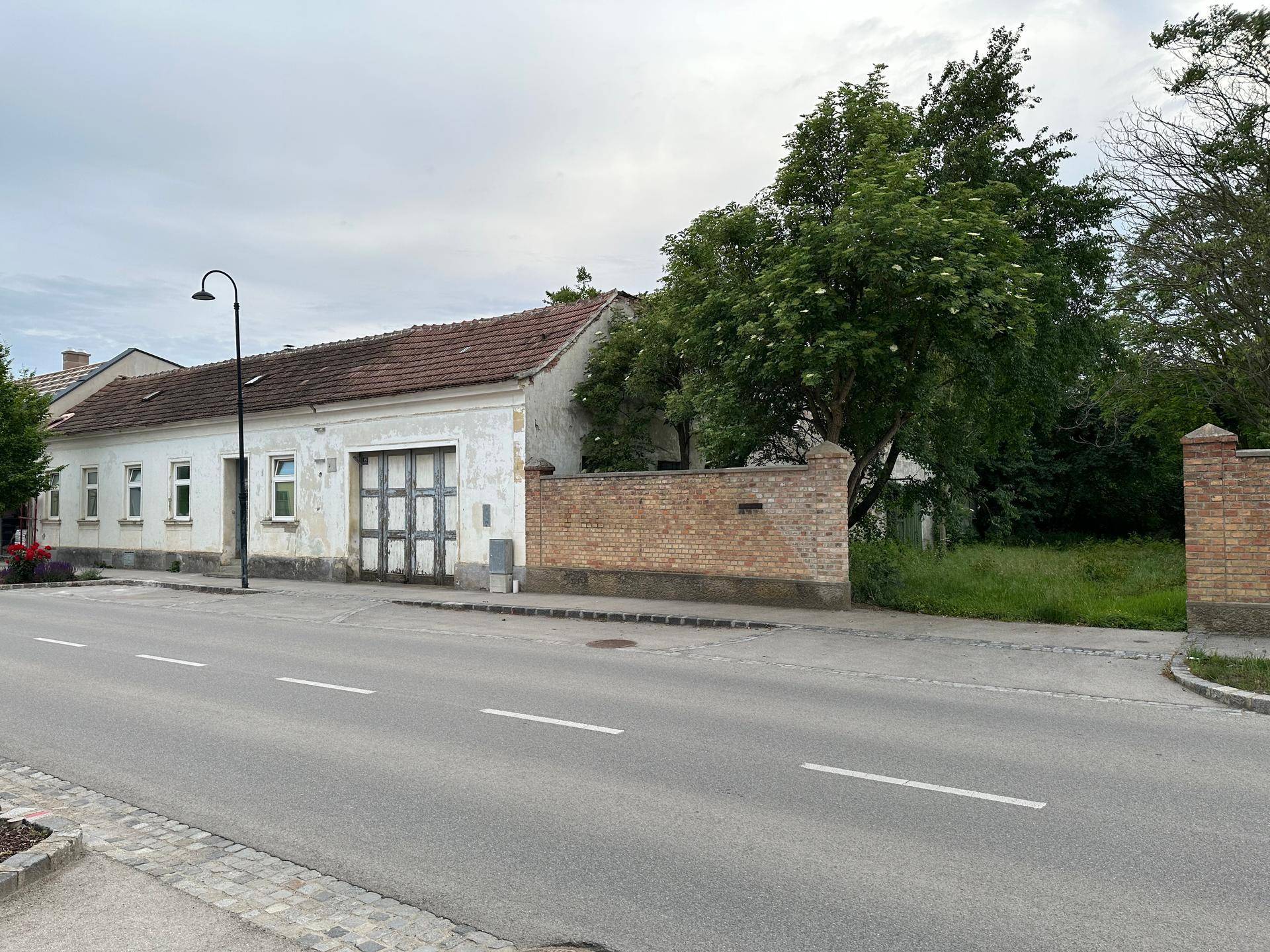 Straßenansicht des Anwesens mit traditioneller Fassade und einer Ziegelmauer.