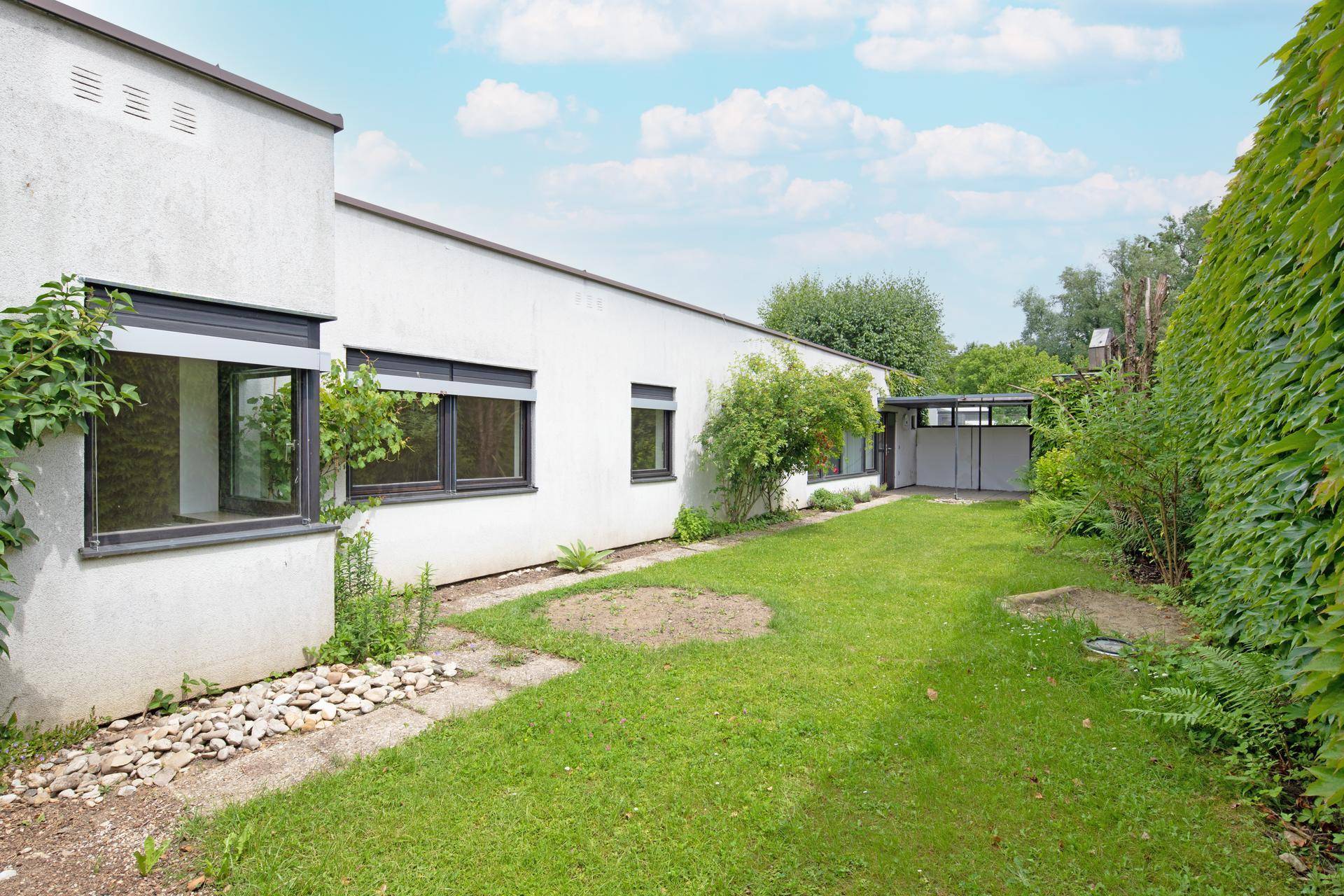 Weitläufiger Gartenbereich mit gepflegtem Rasen und Blick auf die moderne Hausfassade.
