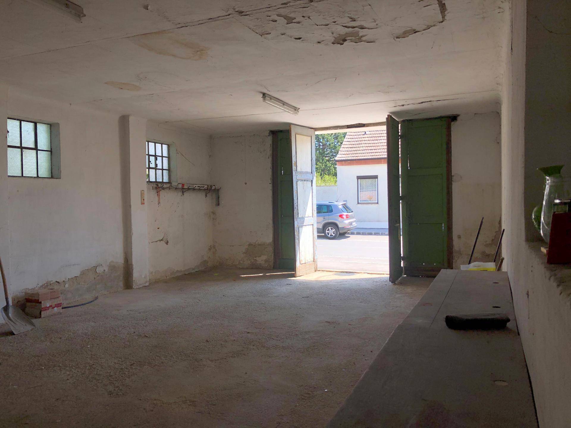 Große Garage oder Werkstatt mit hohen Decken und offenen Toren zur Straße.