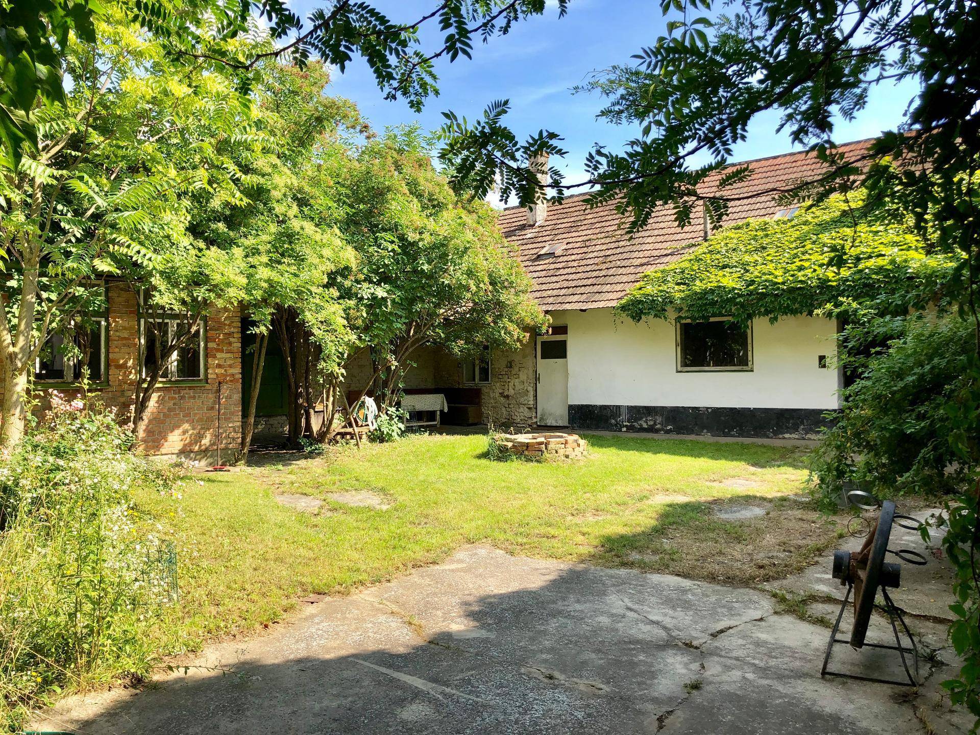 Großer Garten mit Rasenfläche, alten Bäumen und einer Feuerstelle im Freien.