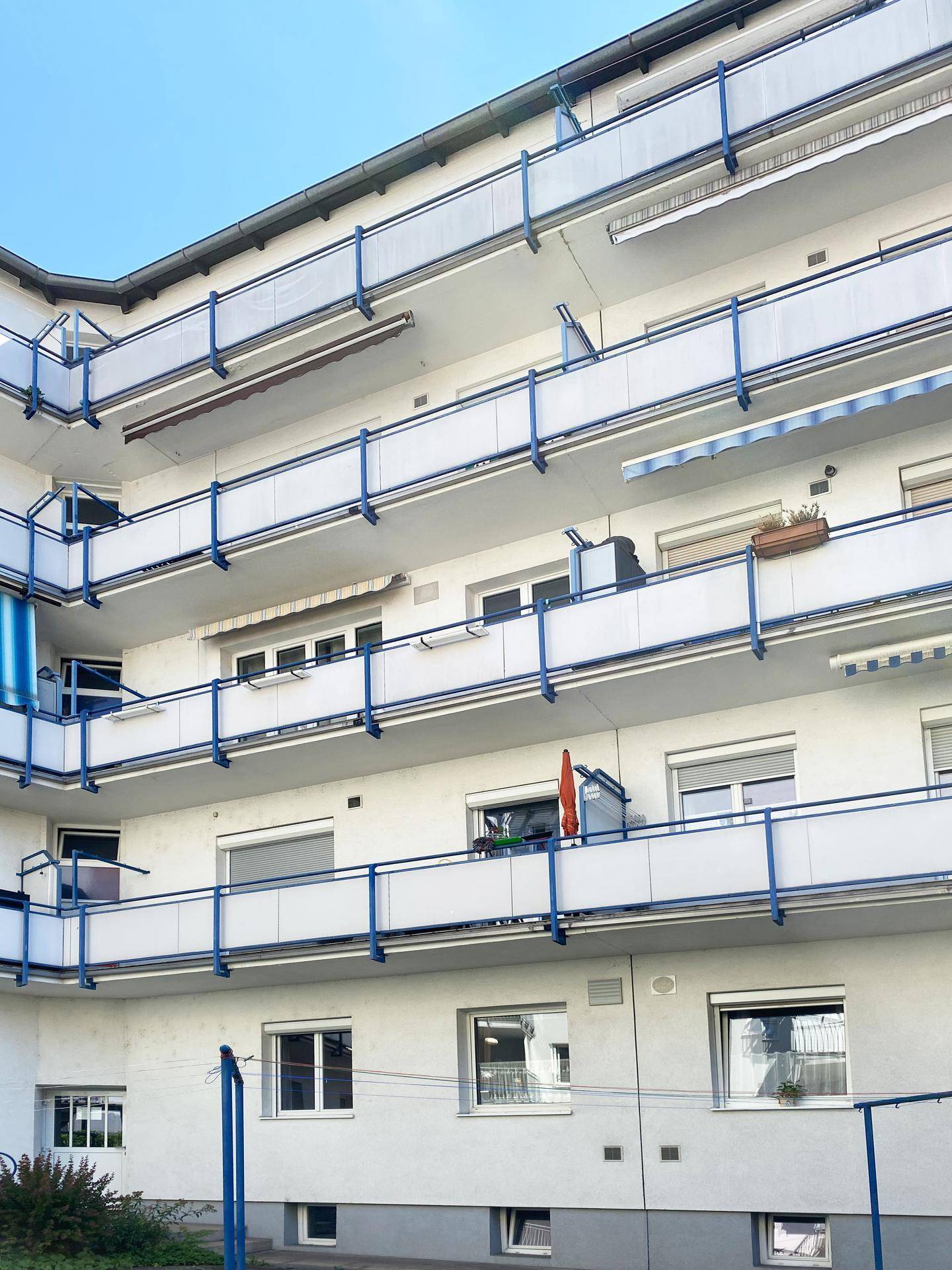 Mehrstöckiges Apartmentgebäude mit zahlreichen Balkonen und blauen Geländern.