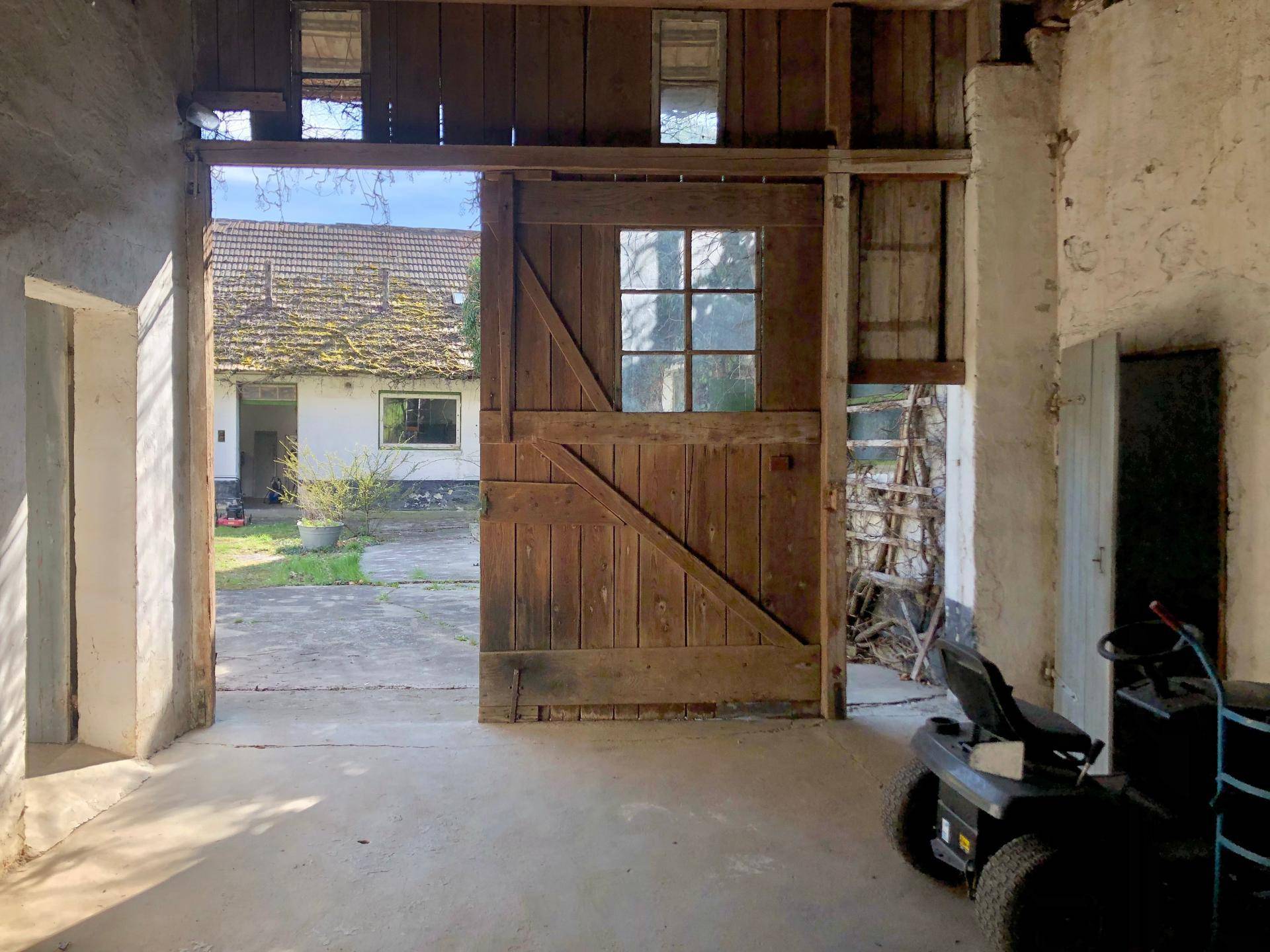 Geräumige Scheune oder Garage mit großen Holztoren und Blick auf den Innenhof.