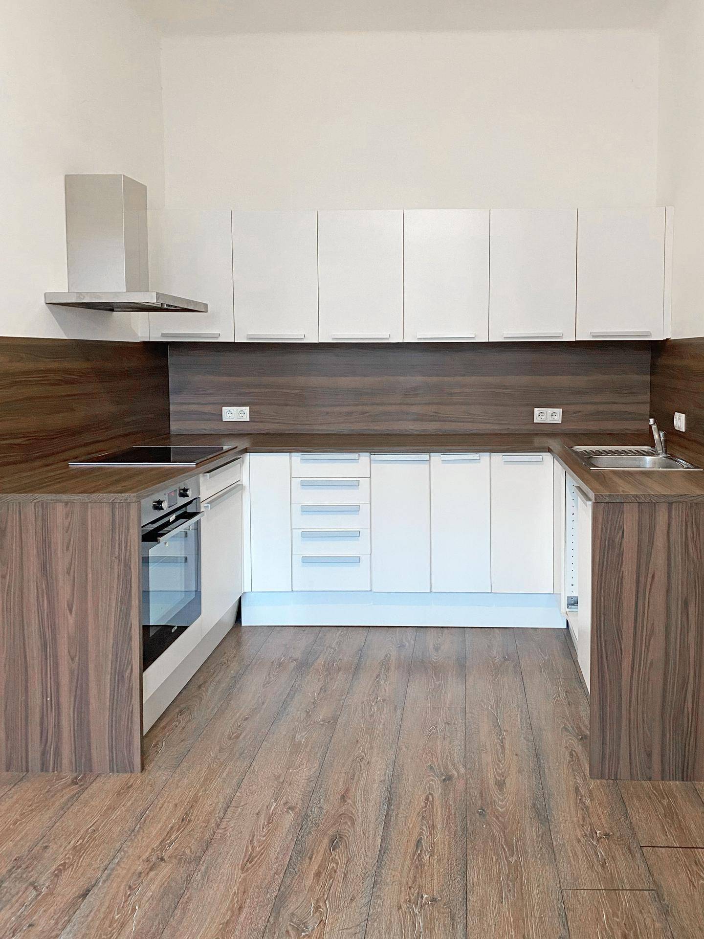 Moderne Einbauküche mit weißen Schränken, Holzoptik-Arbeitsplatten und integrierten Geräten.