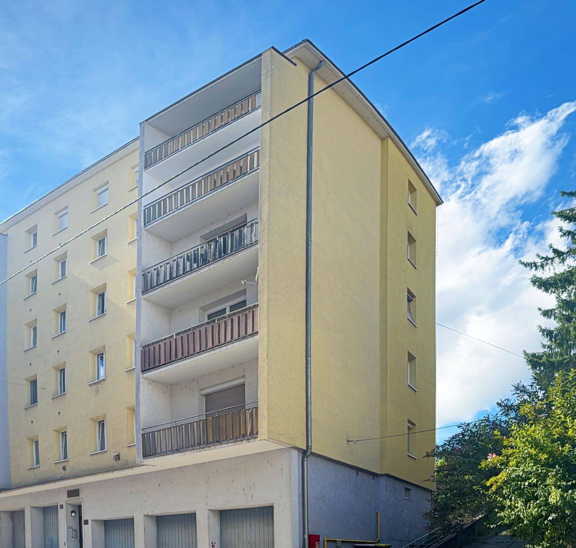 Wohnhaus mit mehreren Etagen, Balkonen und einer hellgelben Außenfassade.