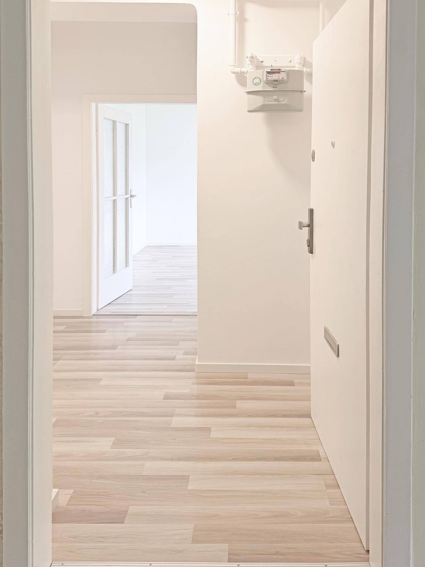 Heller Flur mit modernem Laminatboden und weiß gestrichenen Wänden.