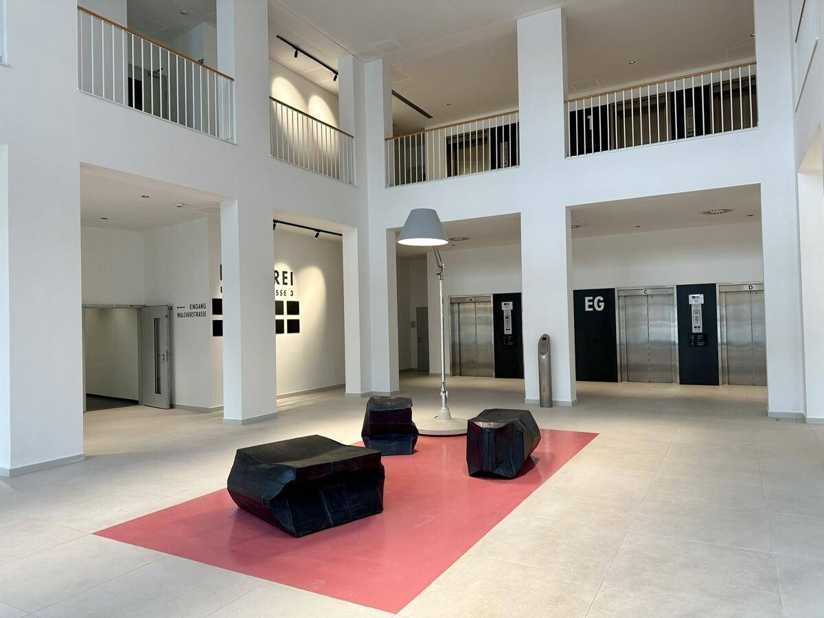 Geräumige, helle Lobby mit hohen Decken, modernen Sitzgelegenheiten und Aufzügen.
