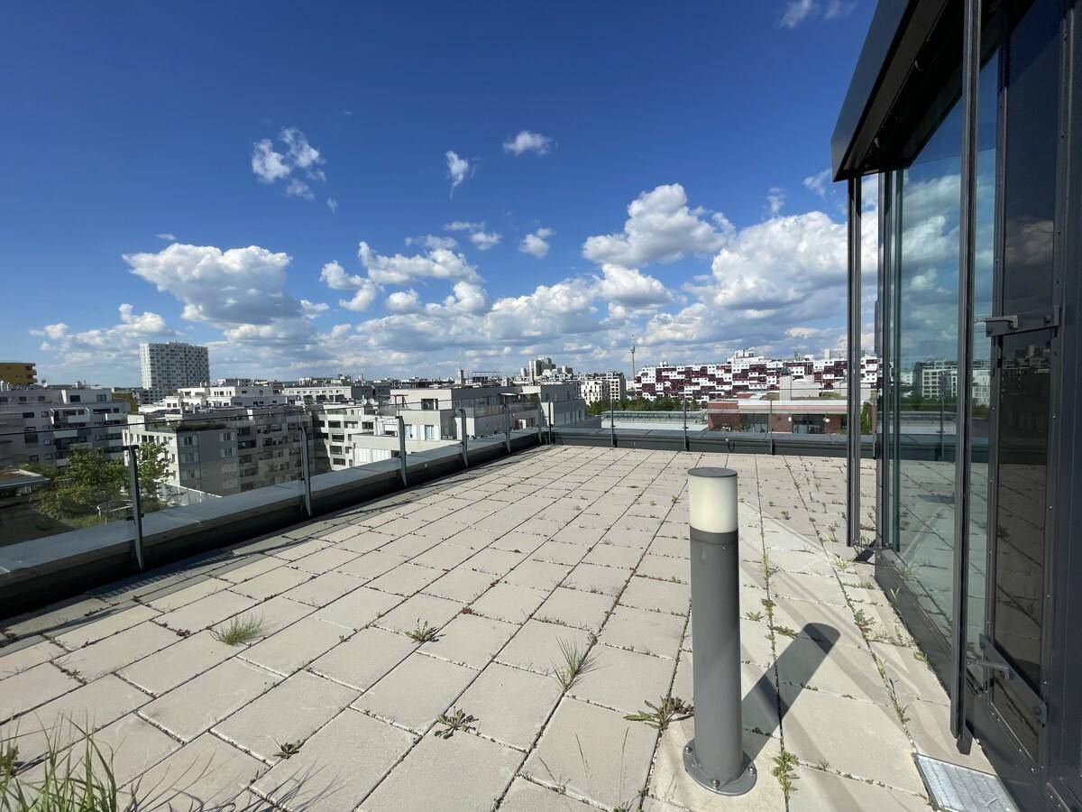 Weitläufige Dachterrasse mit Steinplatten und Panoramablick über die städtische Skyline.