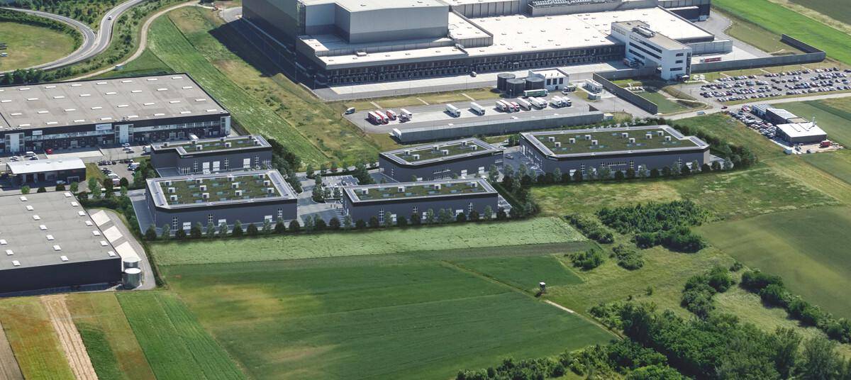 Luftaufnahme eines großen Gewerbekomplexes mit mehreren Gebäuden und umliegenden Feldern.