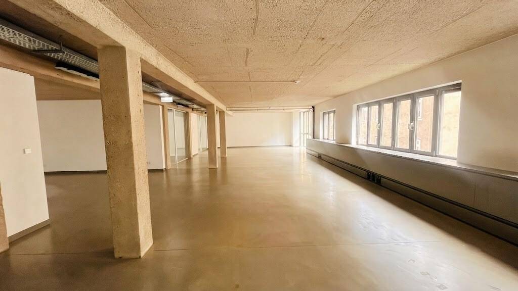 Geräumiger, offener Bürobereich mit Betonstützen und großen Fenstern, die den Raum hell und einladend wirken lassen.