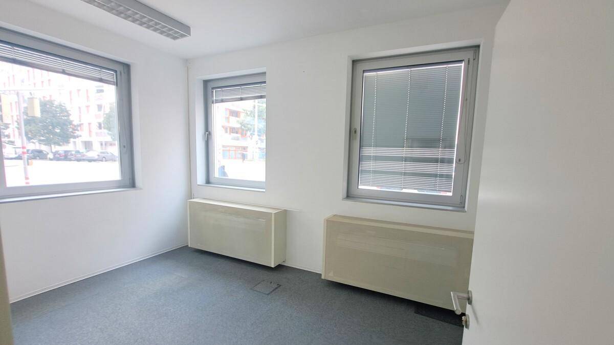 Kleineres, helles Büro mit drei Fenstern, Heizkörpern und grauem Teppichboden.