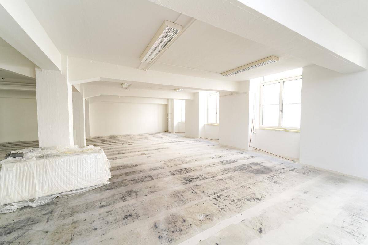 Leerer Raum mit Betonboden, weißen Wänden und Decken, der auf eine Renovierung wartet.
