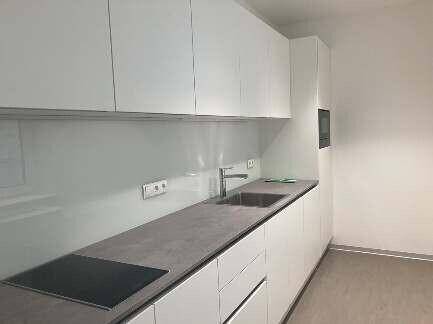 Moderne Einbauküche mit weißen Hochglanzschränken, dunkler Arbeitsplatte und Induktionskochfeld.